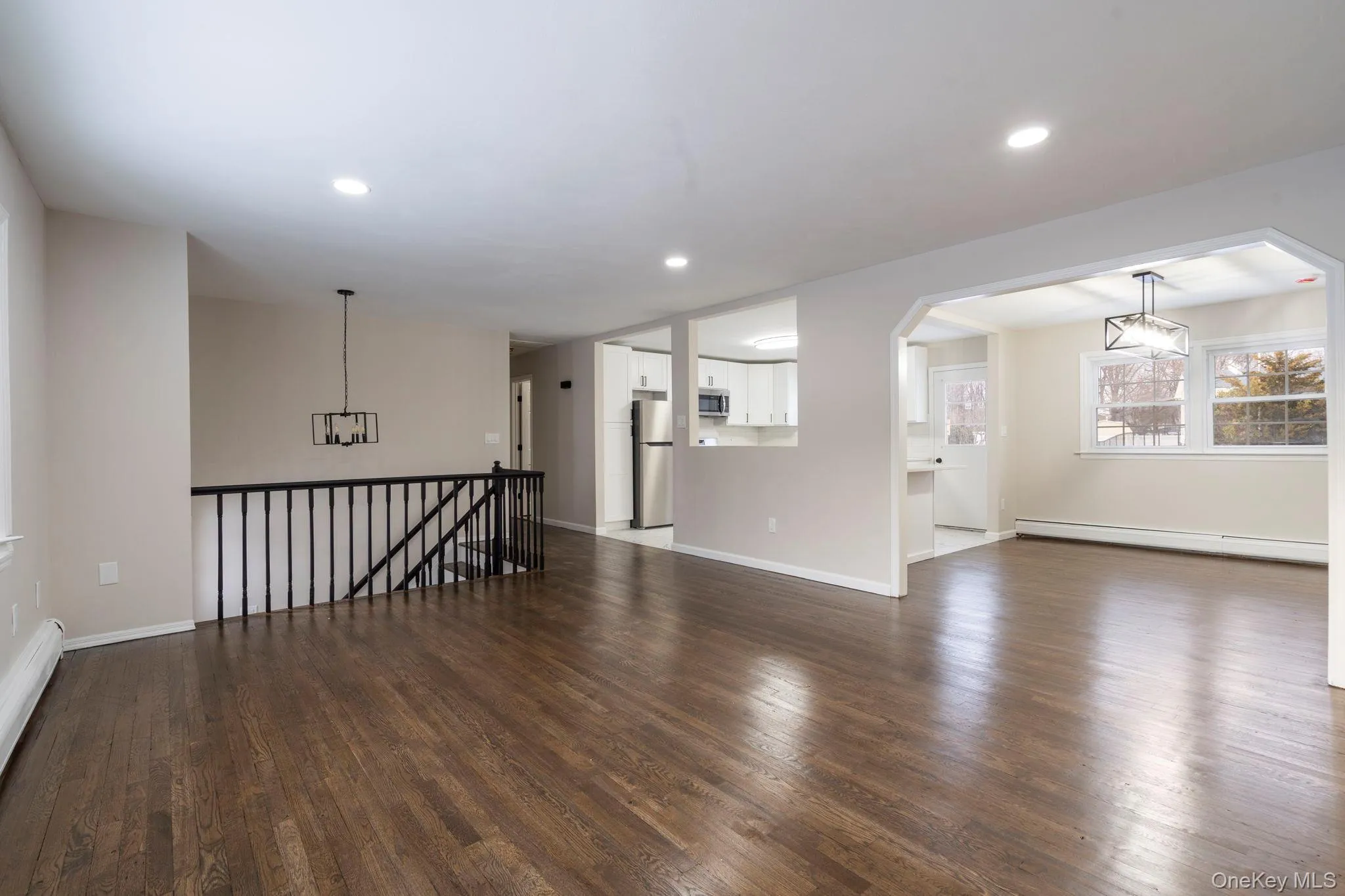 Unfurnished living room with baseboard heating, dark wood-type flooring, a baseboard heating unit, recessed lighting, and a chandelier Unfurnished living room with baseboard heating, dark wood-type flooring, a baseboard heating unit, recessed lighting, and a chandelier