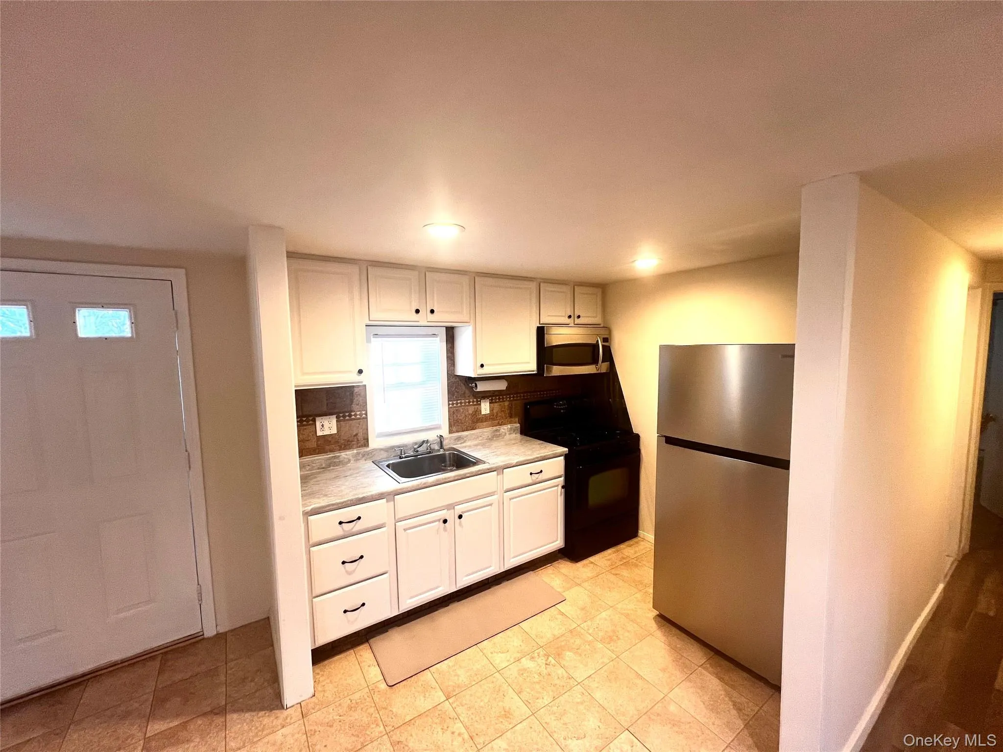 Kitchen with appliances with stainless steel finishes, light countertops, white cabinets, backsplash, and recessed lighting Kitchen with appliances with stainless steel finishes, light countertops, white cabinets, backsplash, and recessed lighting