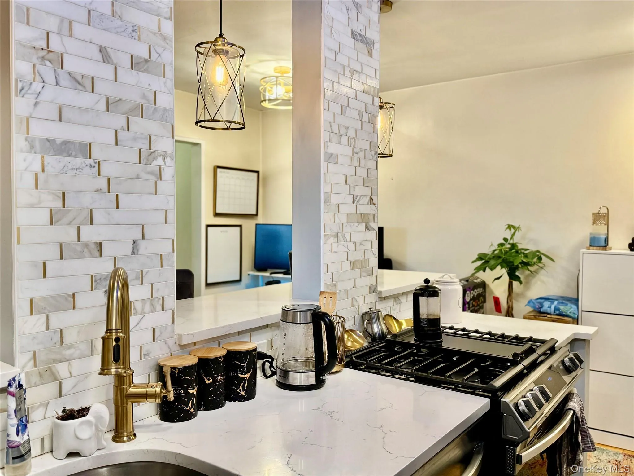 Kitchen featuring gas range, light stone counters, and decorative light fixtures Kitchen featuring gas range, light stone counters, and decorative light fixtures