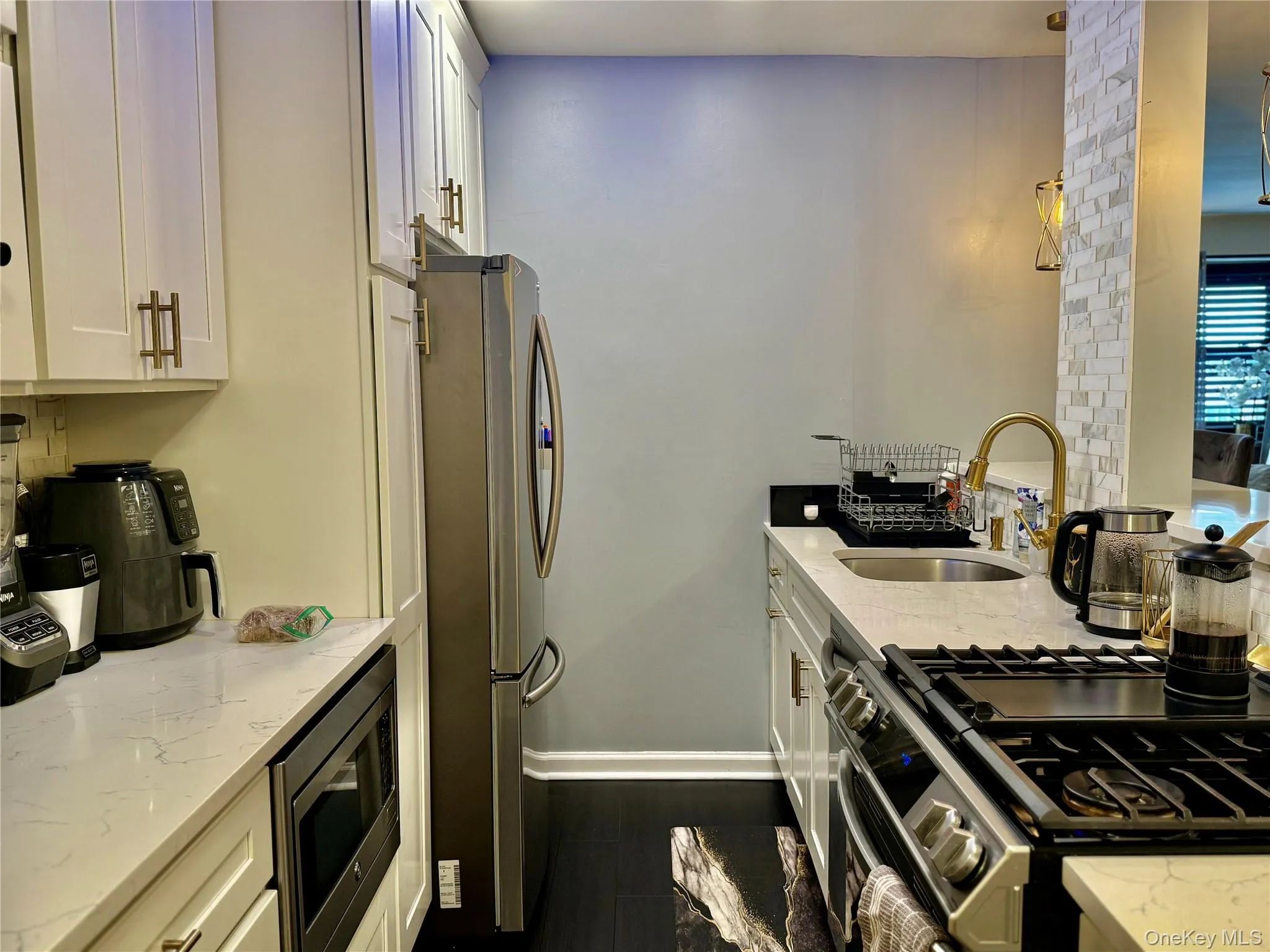 Kitchen featuring white cabinetry, light stone counters, and appliances with stainless steel finishes Kitchen featuring white cabinetry, light stone counters, and appliances with stainless steel finishes