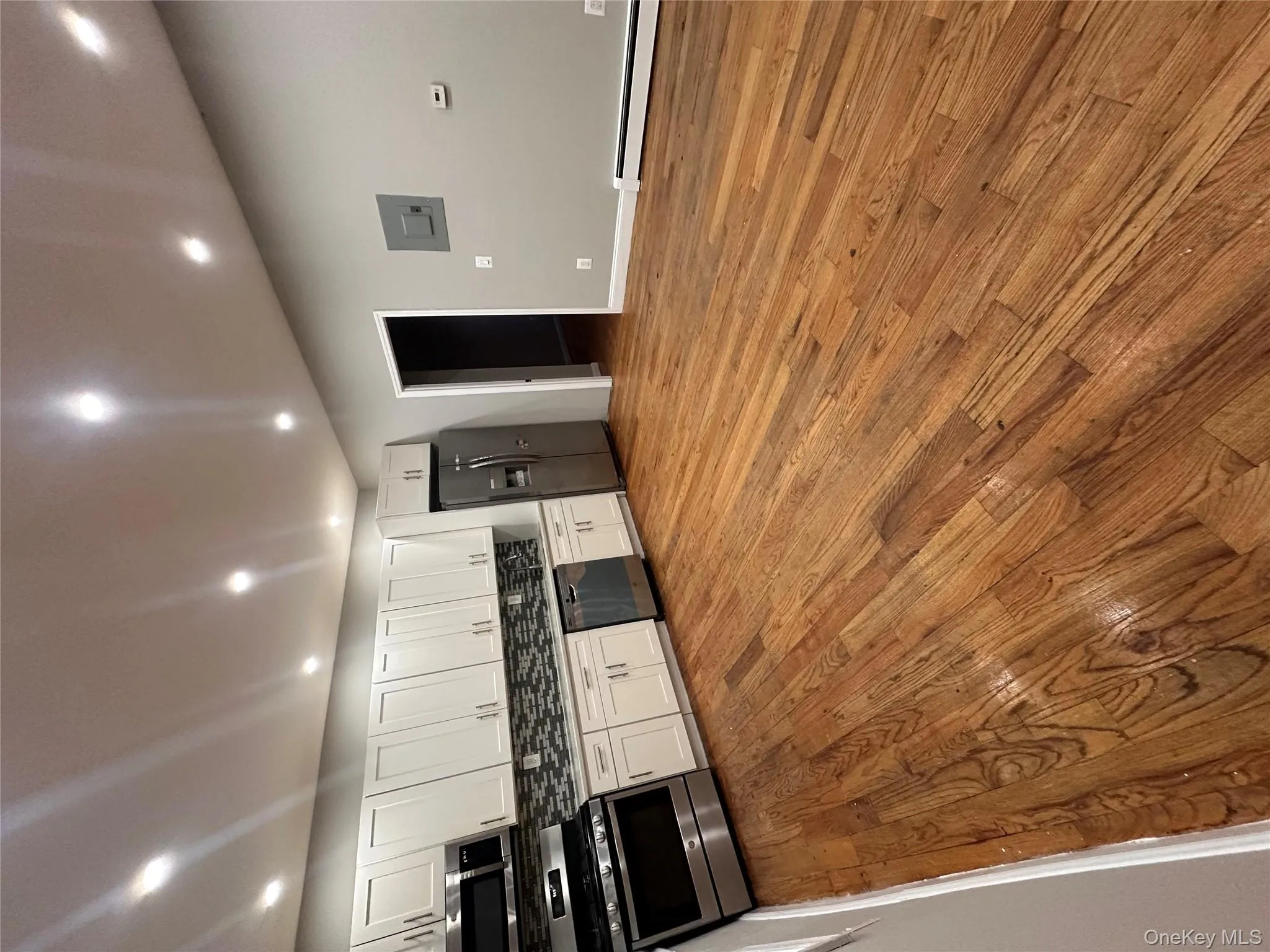 Kitchen featuring appliances with stainless steel finishes, white cabinetry, light wood finished floors, recessed lighting, and a baseboard radiator Kitchen featuring appliances with stainless steel finishes, white cabinetry, light wood finished floors, recessed lighting, and a baseboard radiator