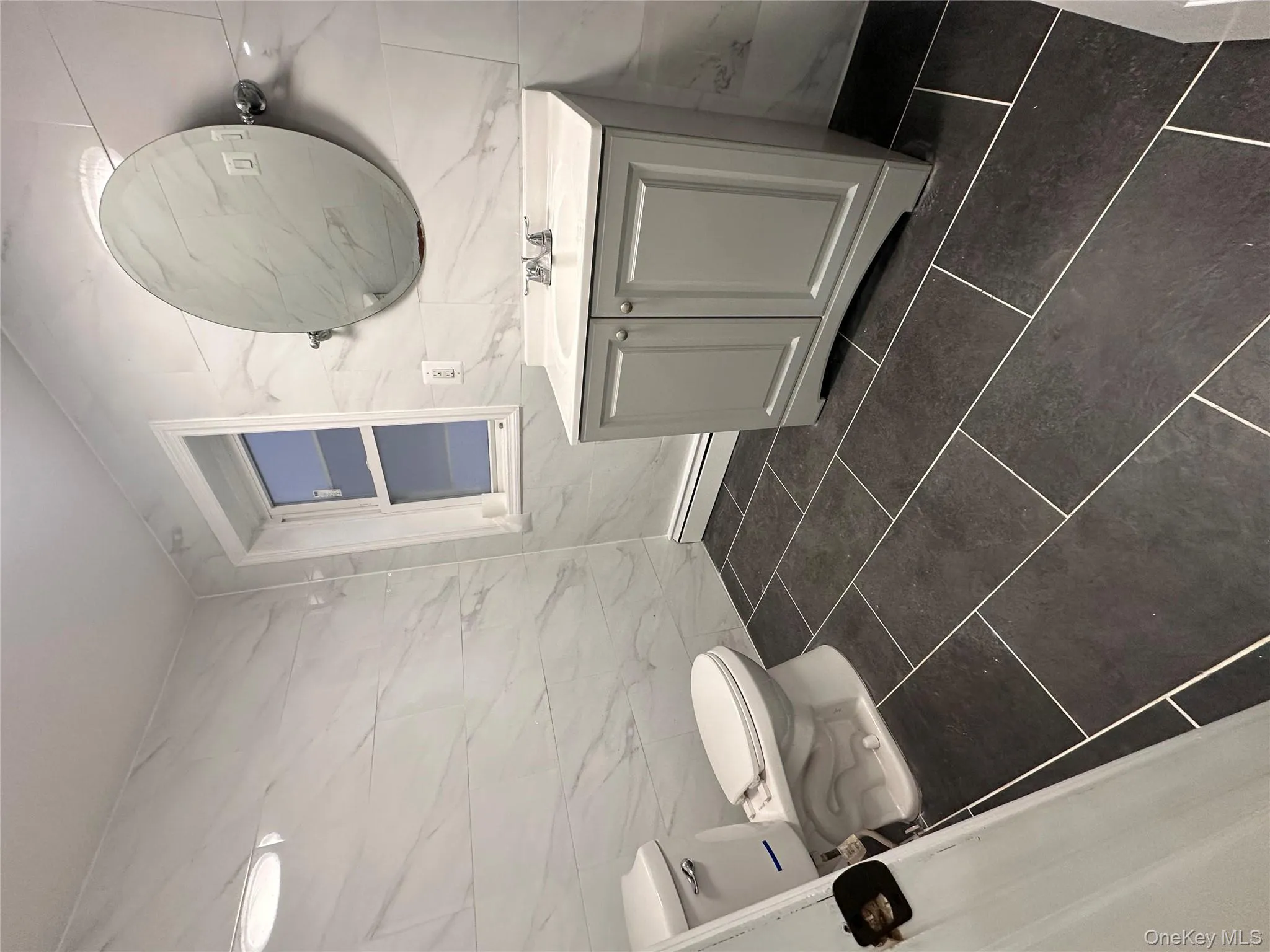 Half bath with tile walls, vanity, dark tile patterned floors, and a baseboard heating unit Half bath with tile walls, vanity, dark tile patterned floors, and a baseboard heating unit