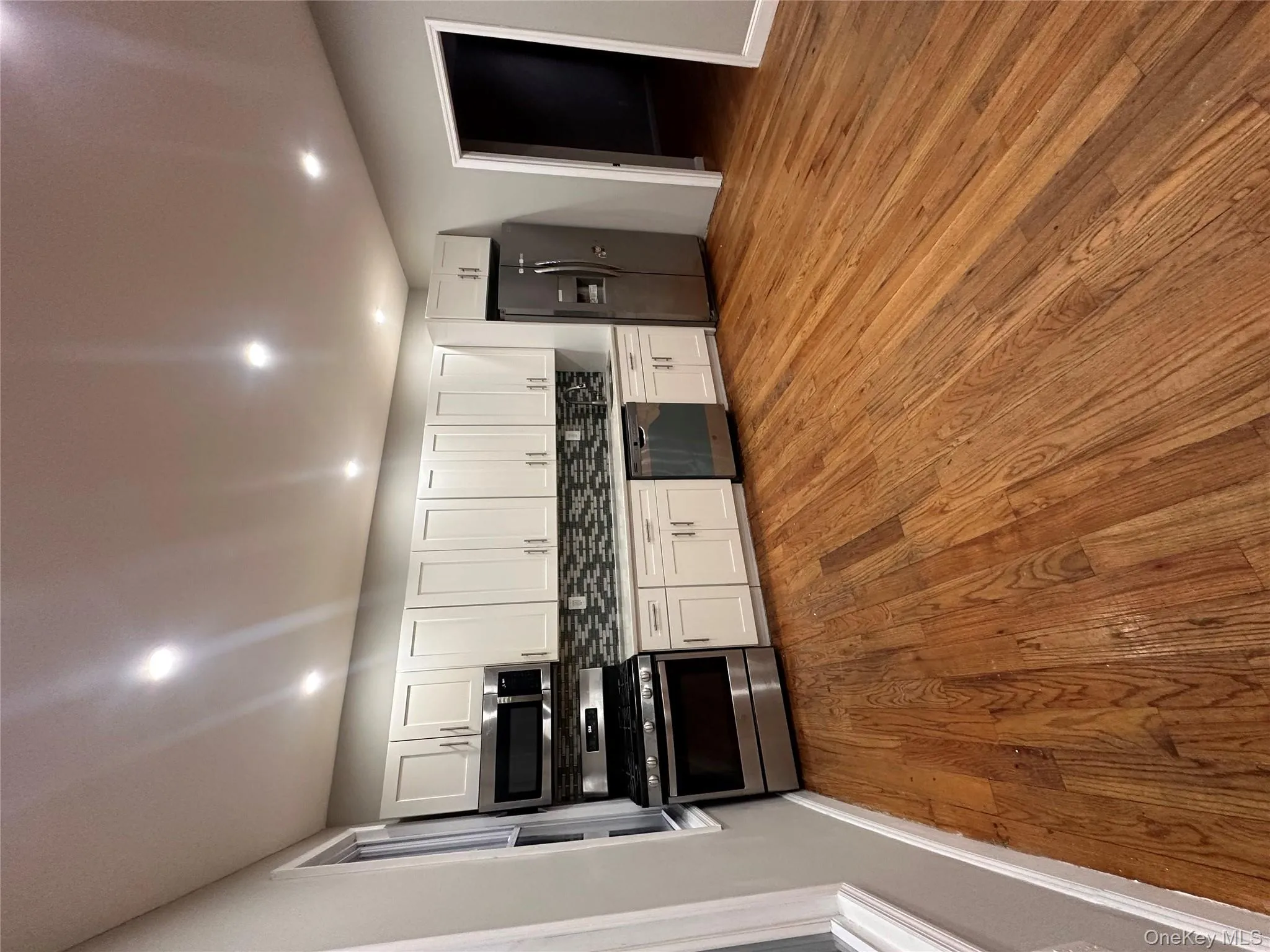Kitchen featuring white cabinetry, stove, fridge, dishwasher, and dark wood-style flooring Kitchen featuring white cabinetry, stove, fridge, dishwasher, and dark wood-style flooring