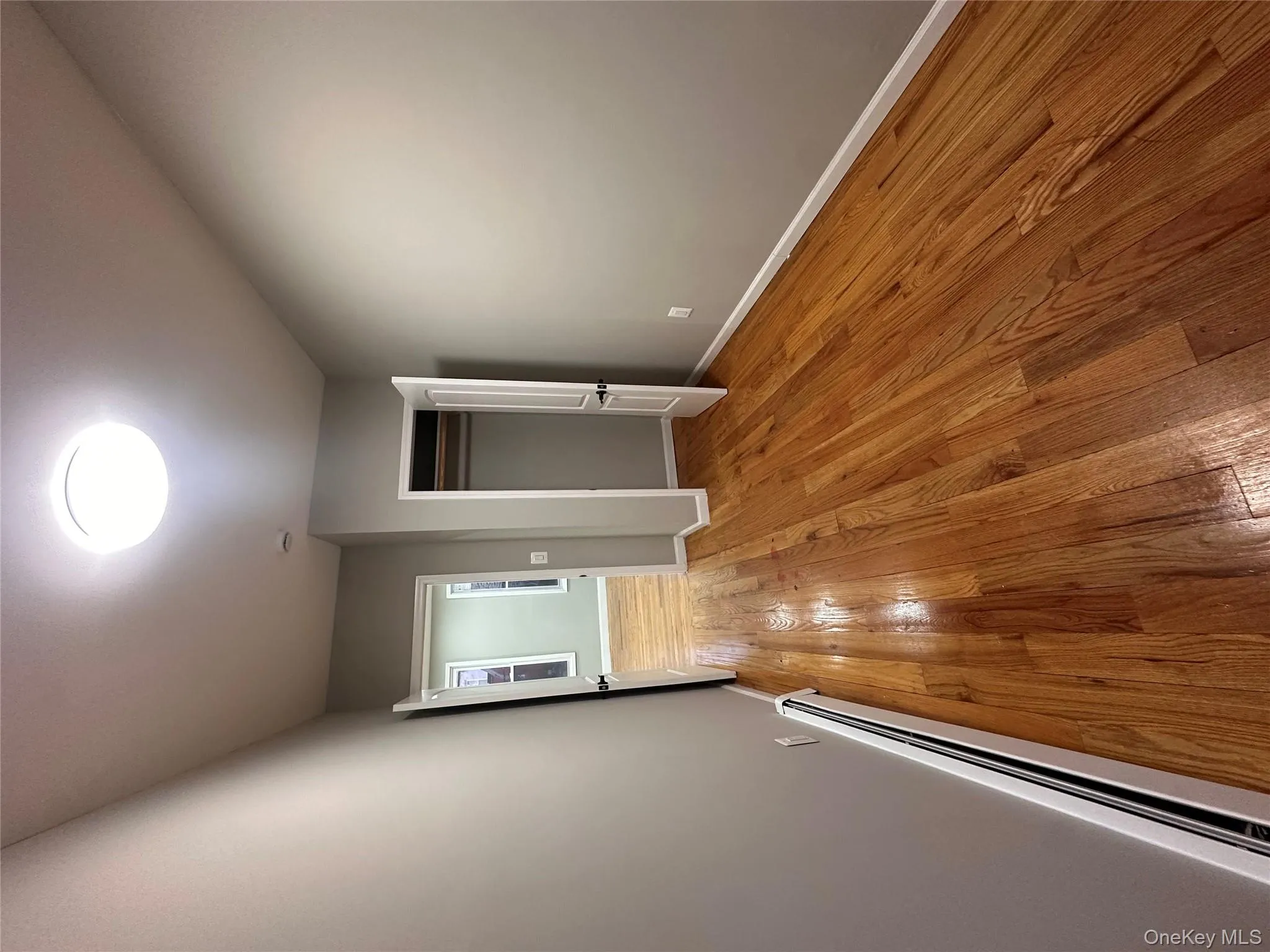 Unfurnished bedroom featuring a baseboard heating unit, a closet, and light wood-style floors Unfurnished bedroom featuring a baseboard heating unit, a closet, and light wood-style floors