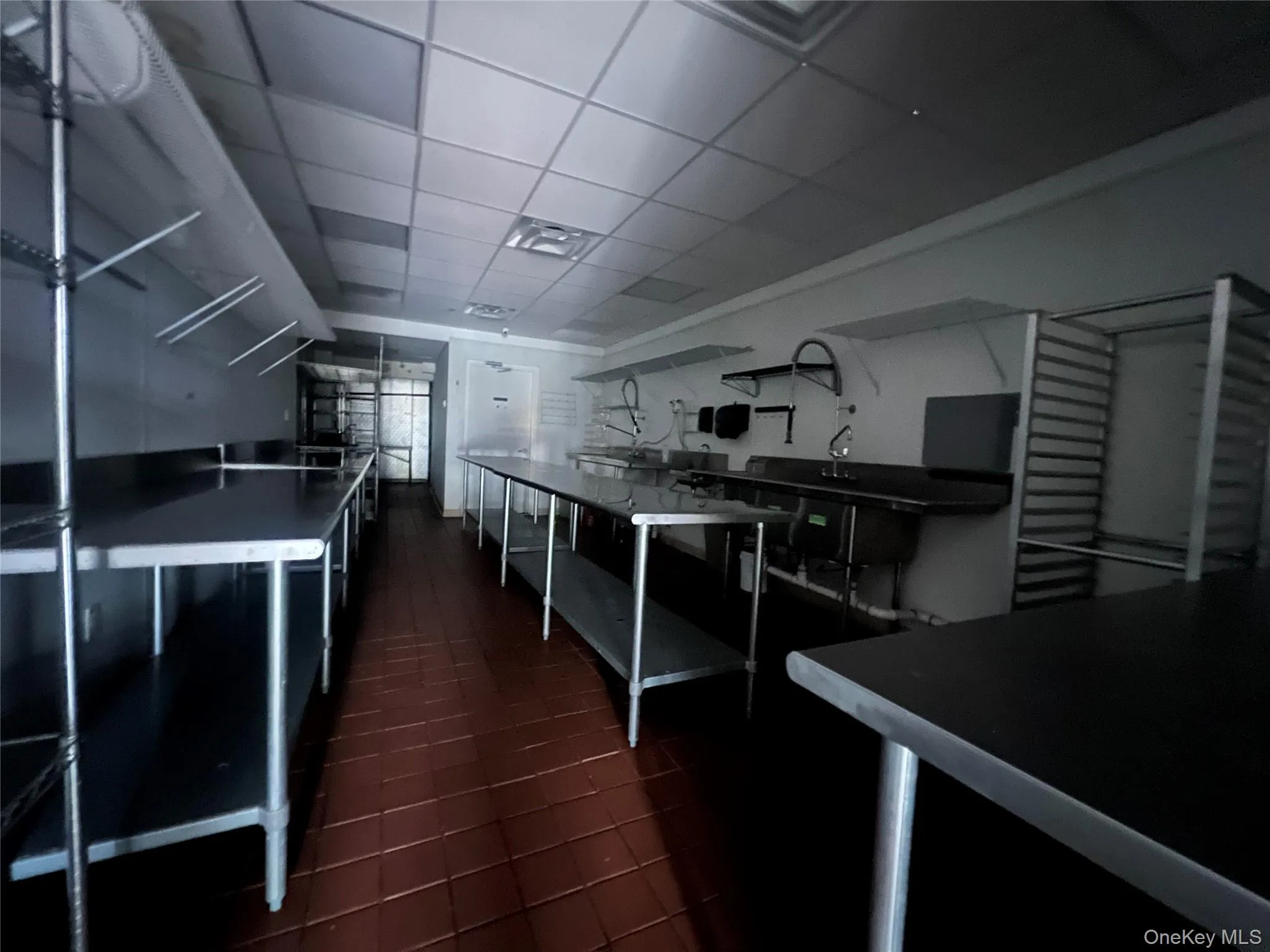 Kitchen with dark cabinets, a paneled ceiling, open shelves, and dark countertops Kitchen with dark cabinets, a paneled ceiling, open shelves, and dark countertops