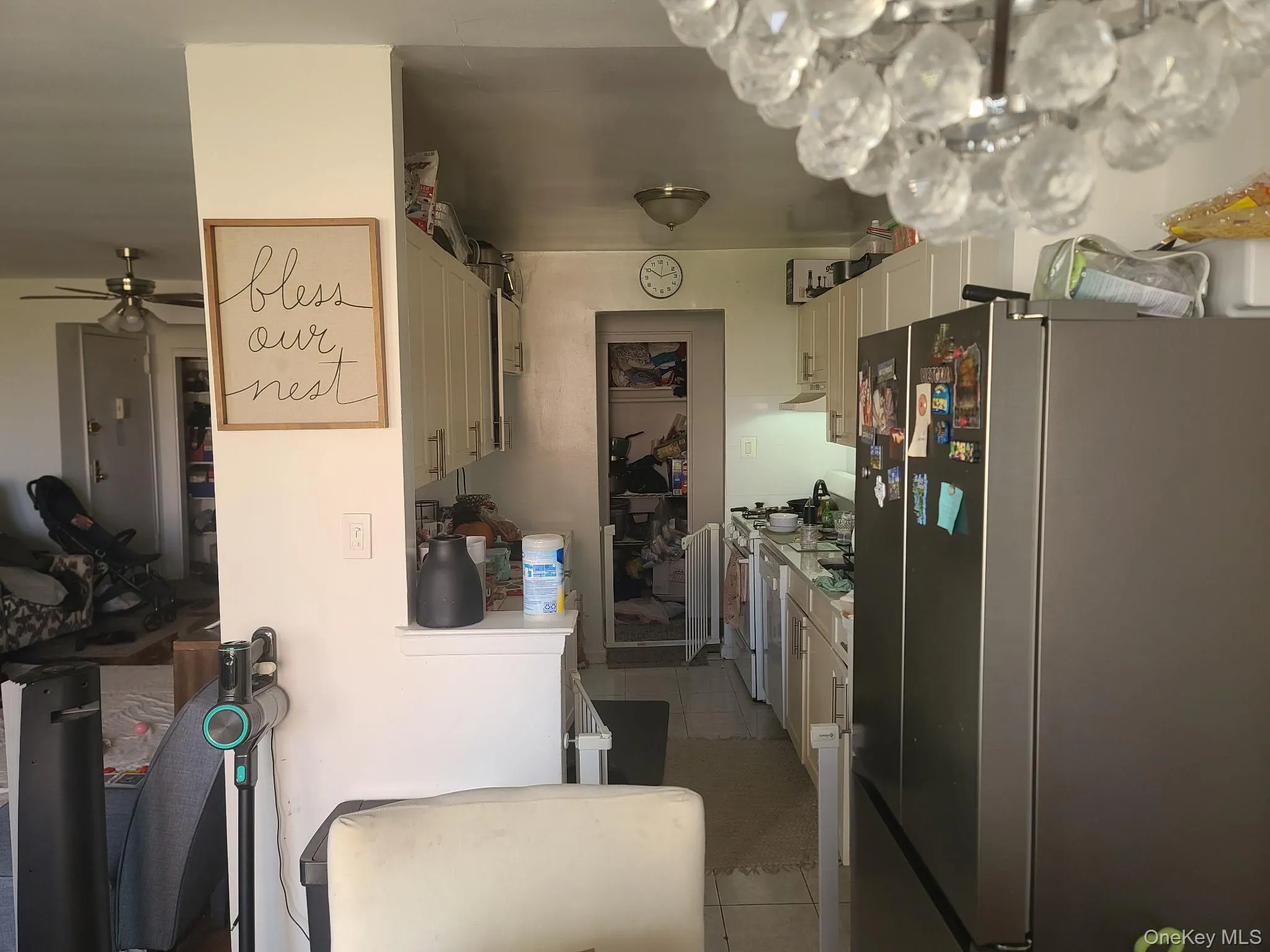 Kitchen with freestanding refrigerator, light countertops, light tile patterned floors, white cabinets, and white range oven Kitchen with freestanding refrigerator, light countertops, light tile patterned floors, white cabinets, and white range oven