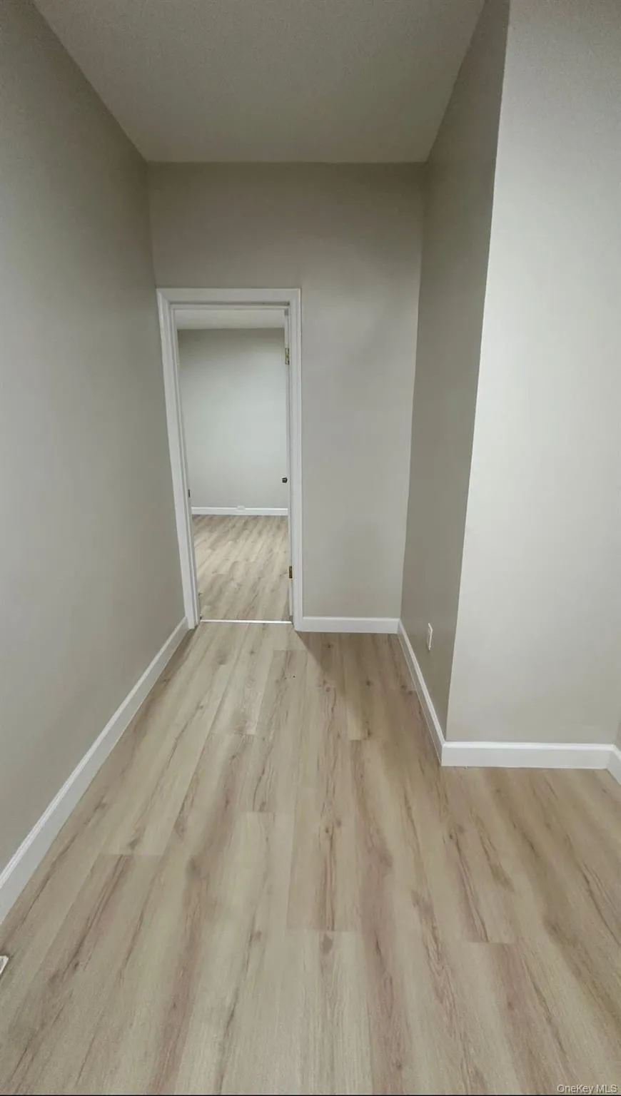 Hallway featuring baseboards and light wood-style floors Hallway featuring baseboards and light wood-style floors