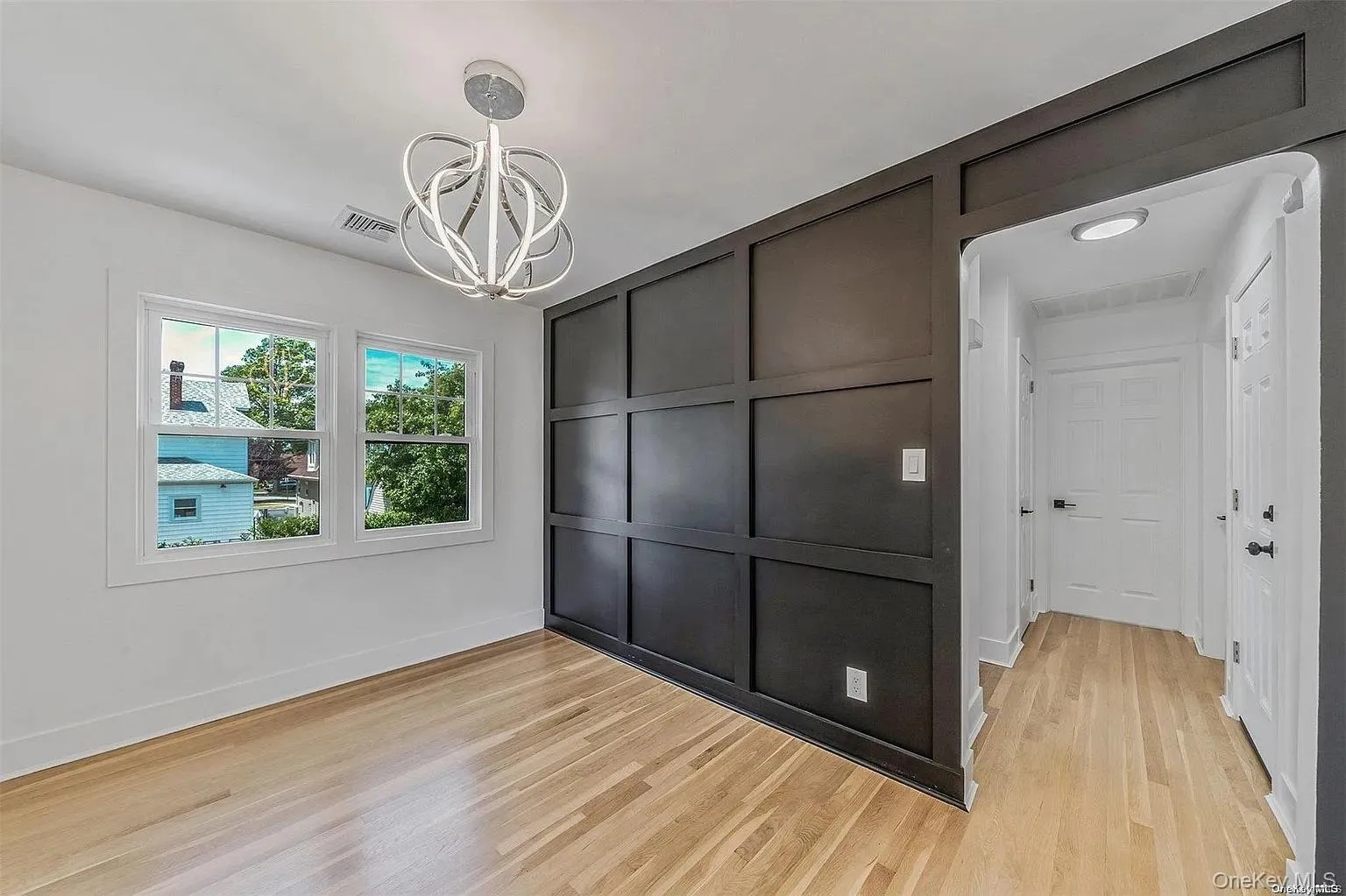 Unfurnished dining area with light wood-style flooring, a chandelier, and a decorative wall Unfurnished dining area with light wood-style flooring, a chandelier, and a decorative wall
