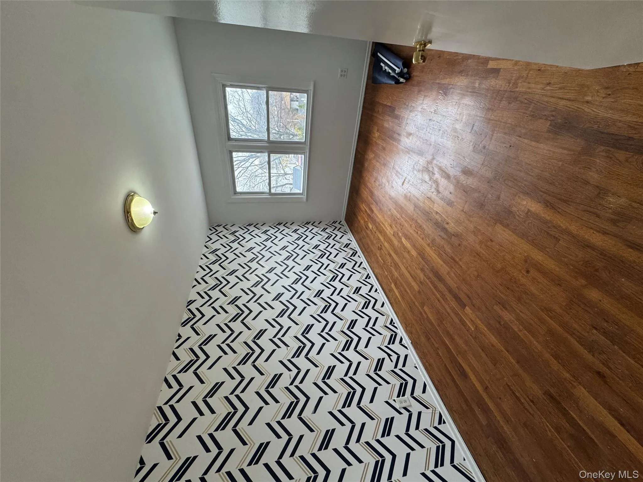 Unfurnished room featuring an accent wall, wood finished floors, and wallpapered walls Unfurnished room featuring an accent wall, wood finished floors, and wallpapered walls