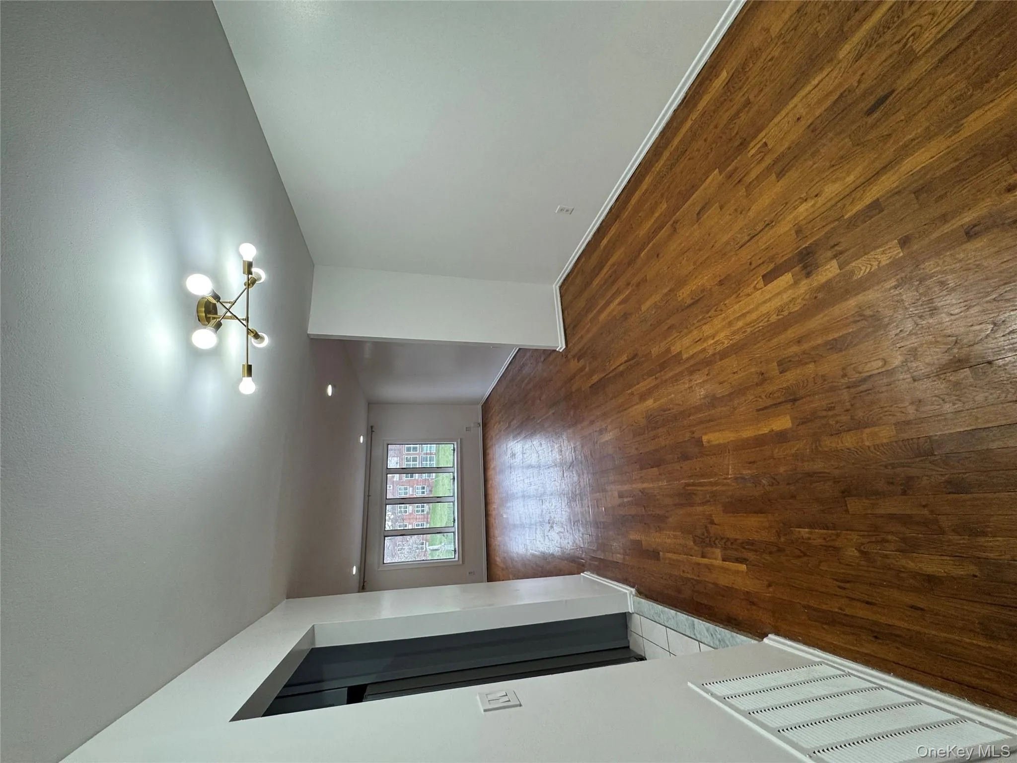 Empty room with a chandelier and dark wood-style flooring Empty room with a chandelier and dark wood-style flooring