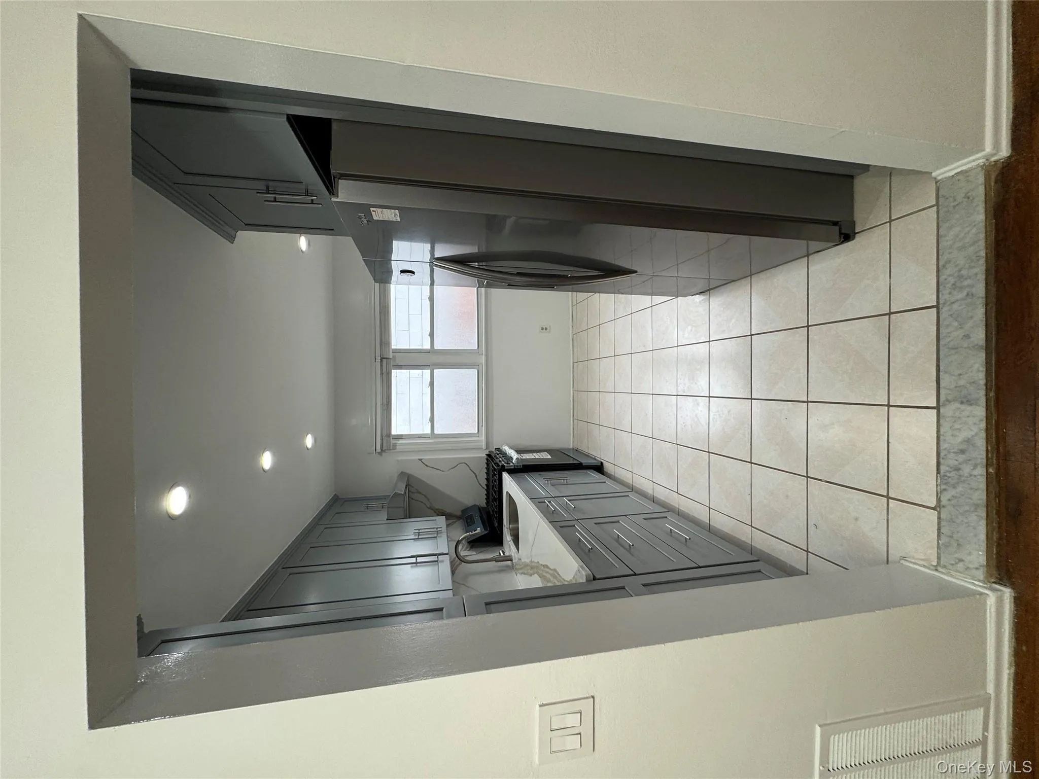 Kitchen featuring fridge, range, light tile patterned floors, recessed lighting, and gray cabinetry Kitchen featuring fridge, range, light tile patterned floors, recessed lighting, and gray cabinetry