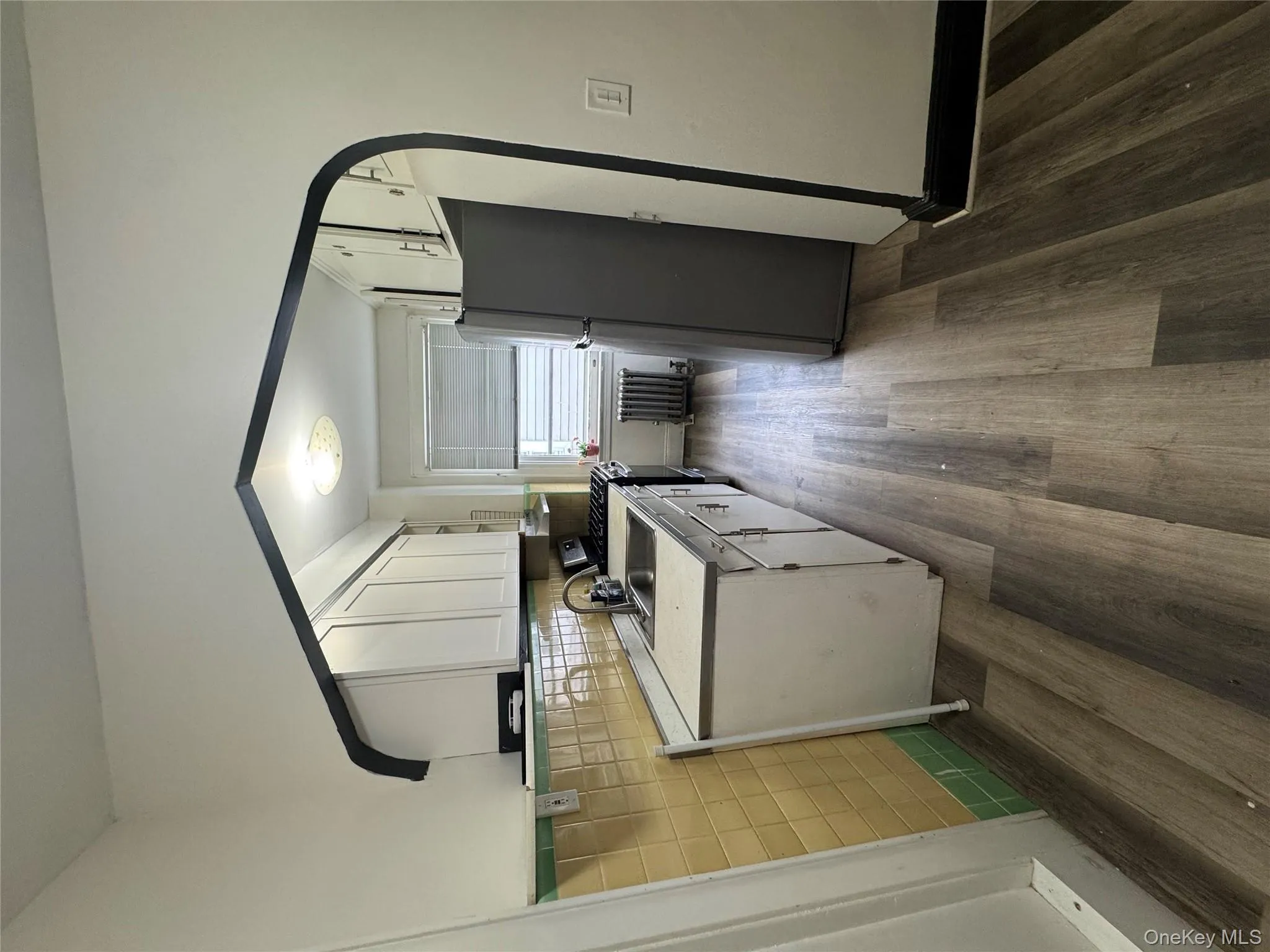 Kitchen with white cabinetry, light countertops, fridge, gas range, and dark wood finished floors Kitchen with white cabinetry, light countertops, fridge, gas range, and dark wood finished floors