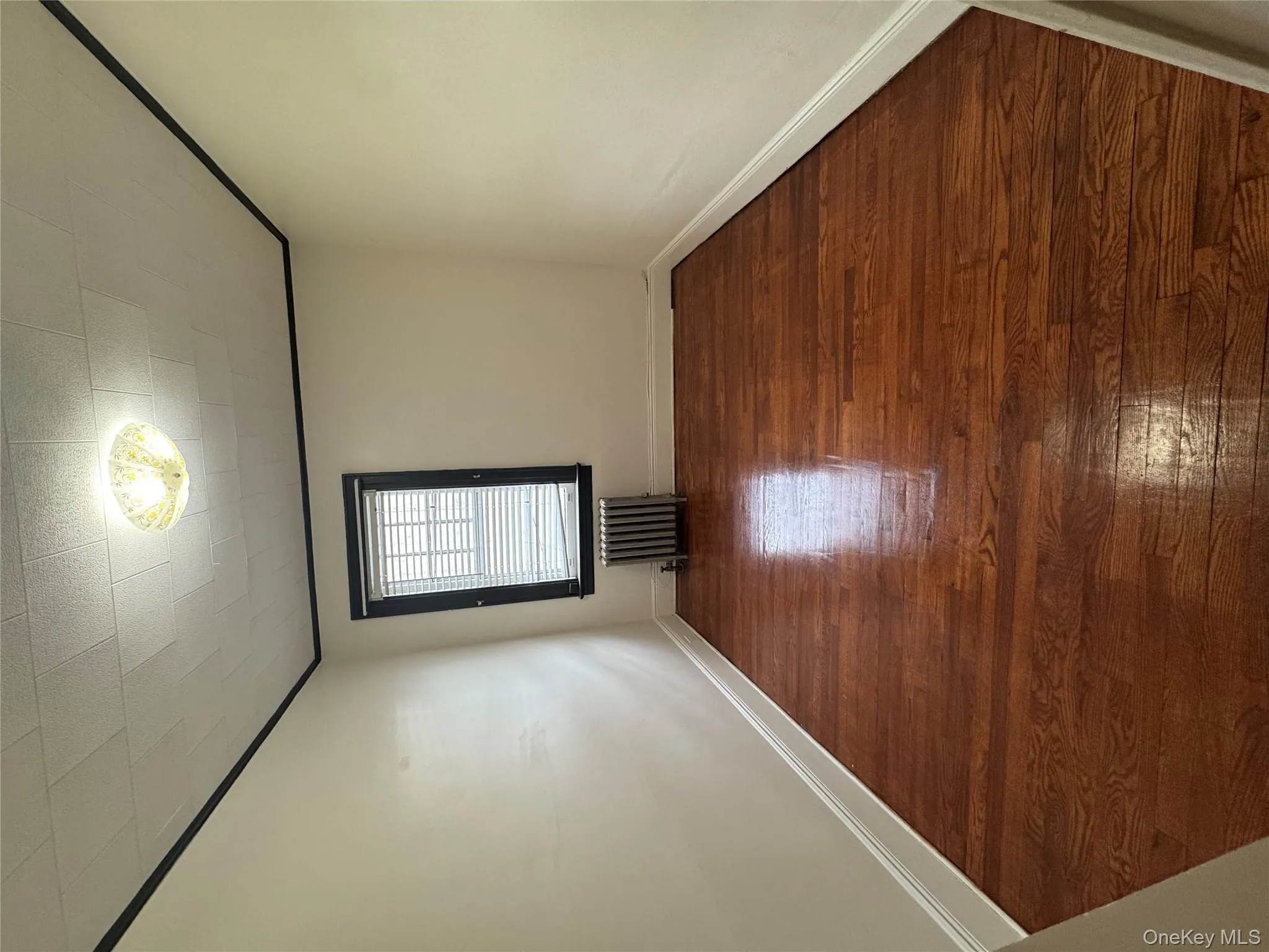 Empty room featuring dark wood-style floors and radiator heating unit Empty room featuring dark wood-style floors and radiator heating unit
