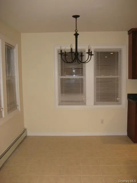 Unfurnished dining area featuring a baseboard heating unit and light tile patterned floors Unfurnished dining area featuring a baseboard heating unit and light tile patterned floors