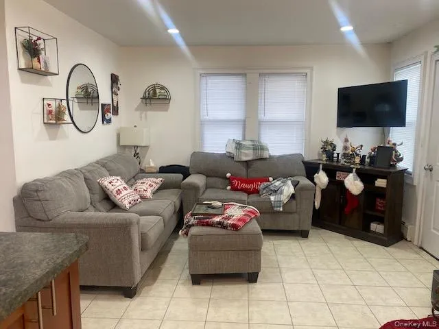 Living room featuring light tile patterned floors, recessed lighting, and a baseboard radiator Living room featuring light tile patterned floors, recessed lighting, and a baseboard radiator
