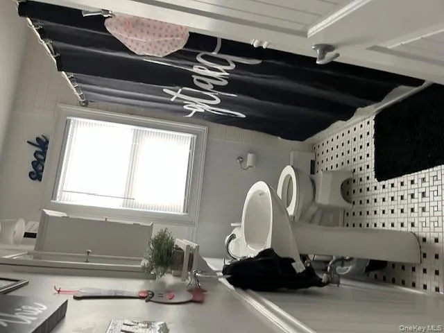 Full bath featuring curtained shower, a baseboard heating unit, and light tile patterned flooring Full bath featuring curtained shower, a baseboard heating unit, and light tile patterned flooring