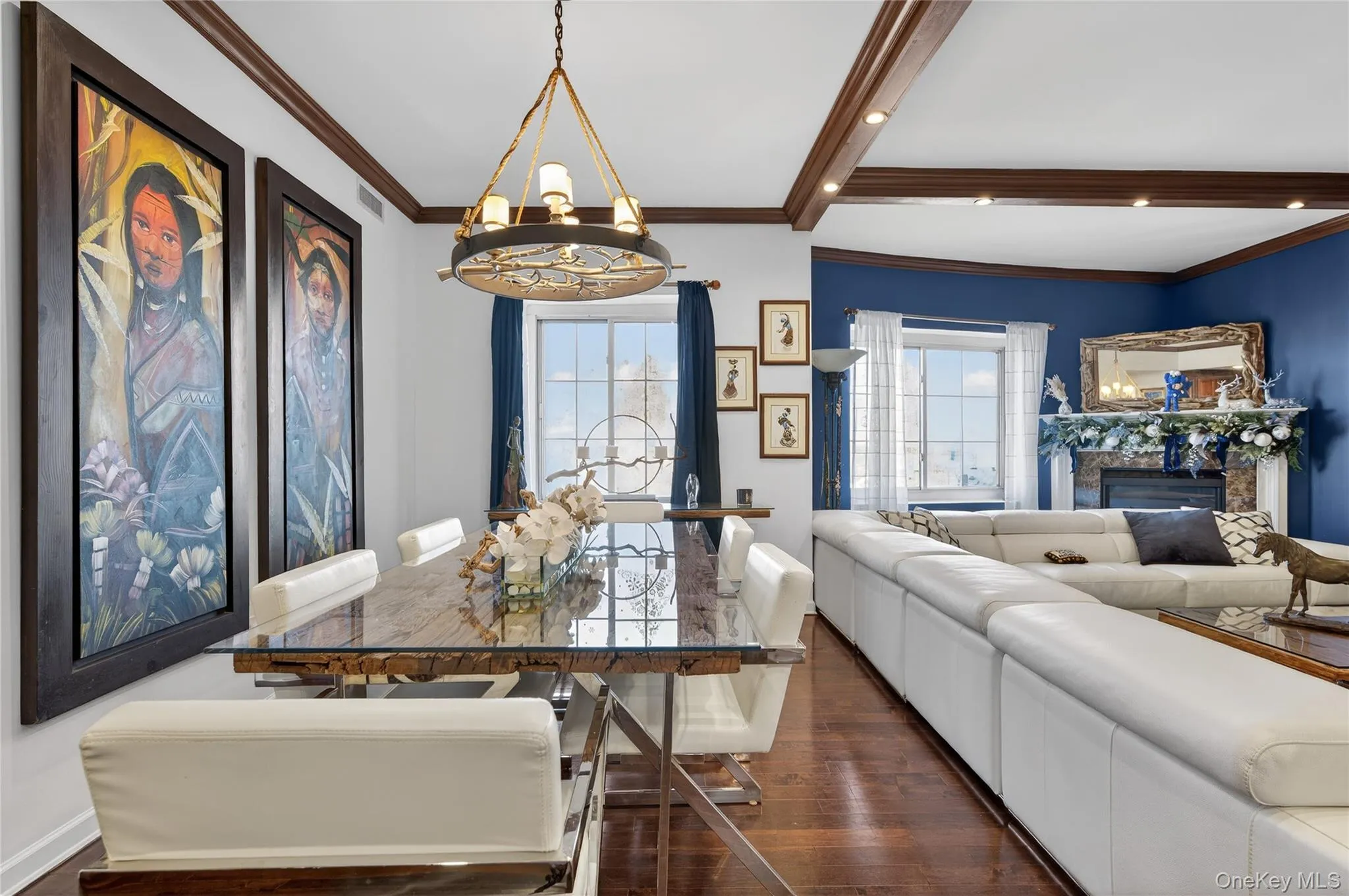 Dining space featuring a chandelier, crown molding, dark wood-style floors, and a fireplace Dining space featuring a chandelier, crown molding, dark wood-style floors, and a fireplace