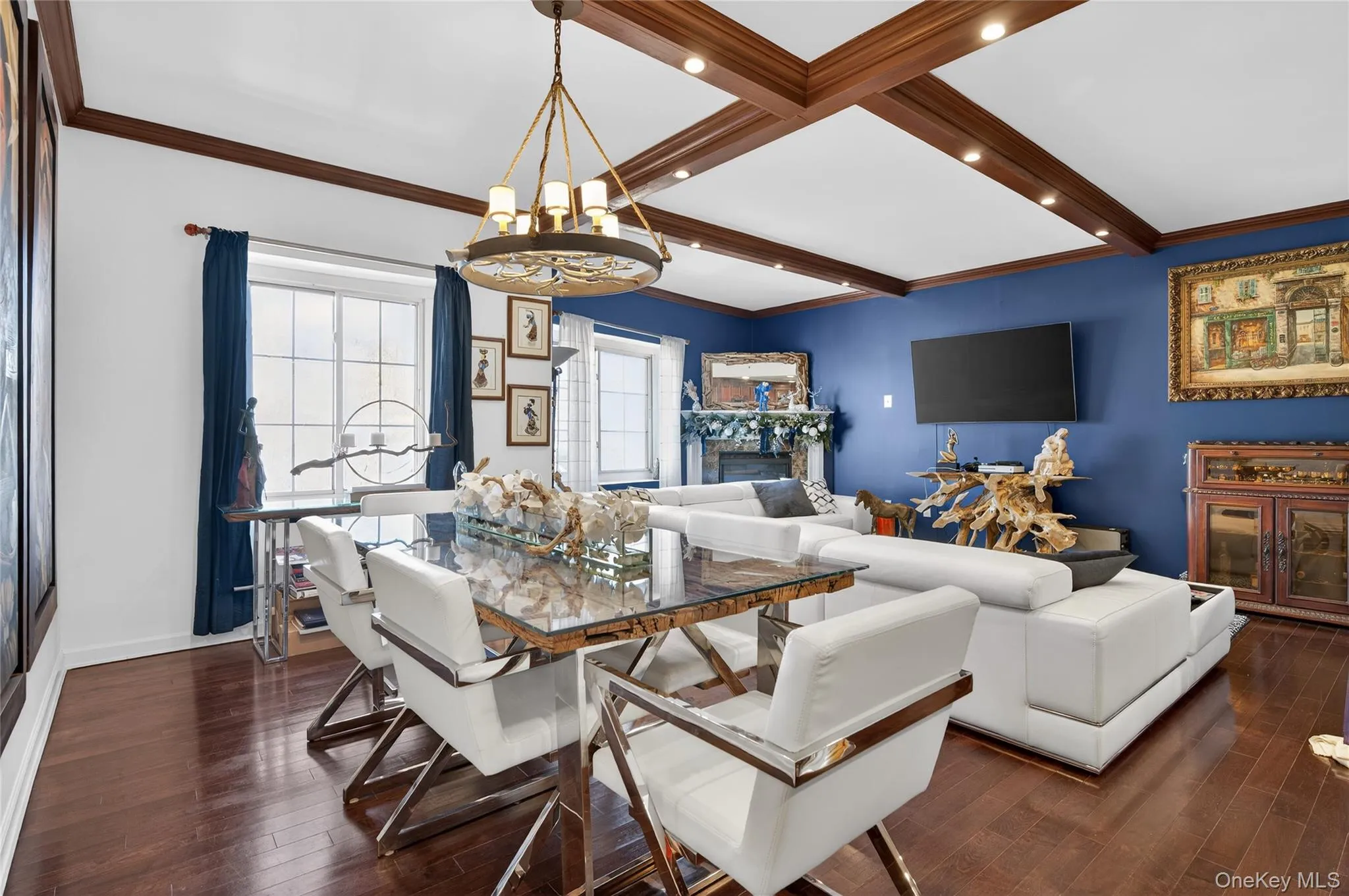 Dining area featuring a fireplace, beam ceiling, ornamental molding, dark wood-style flooring, and a chandelier Dining area featuring a fireplace, beam ceiling, ornamental molding, dark wood-style flooring, and a chandelier