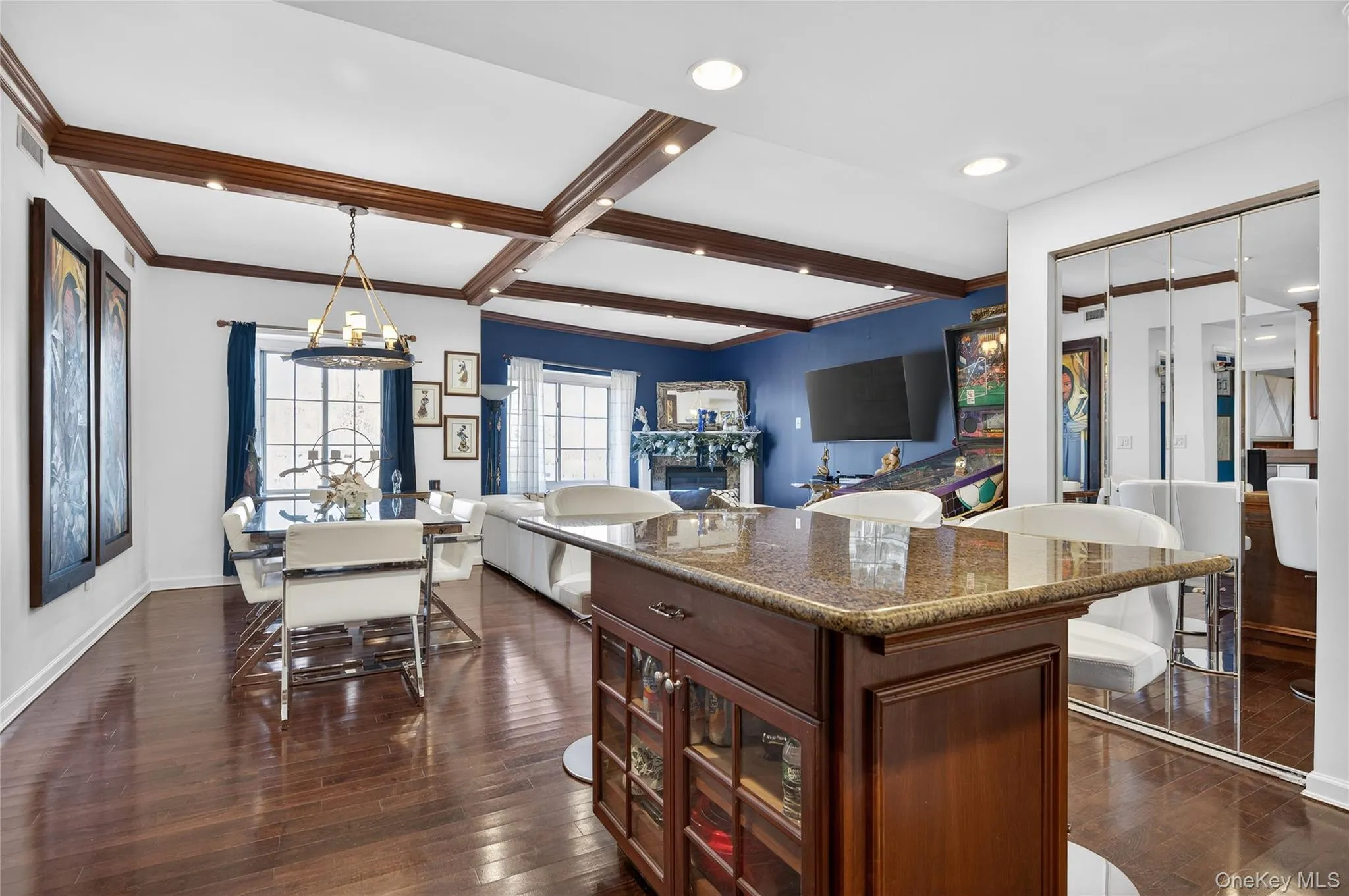 Kitchen featuring dark stone countertops, beam ceiling, a glass covered fireplace, open floor plan, and a center island Kitchen featuring dark stone countertops, beam ceiling, a glass covered fireplace, open floor plan, and a center island