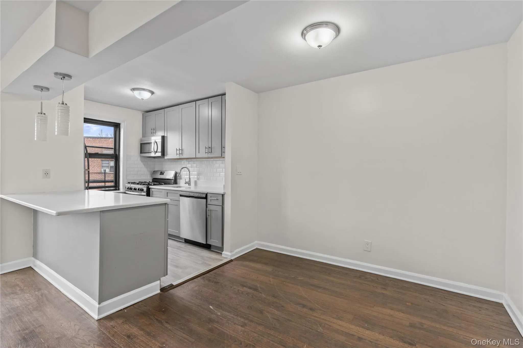 Kitchen featuring gray cabinetry, pendant lighting, dark wood-type flooring, and appliances with stainless steel finishes Kitchen featuring gray cabinetry, pendant lighting, dark wood-type flooring, and appliances with stainless steel finishes