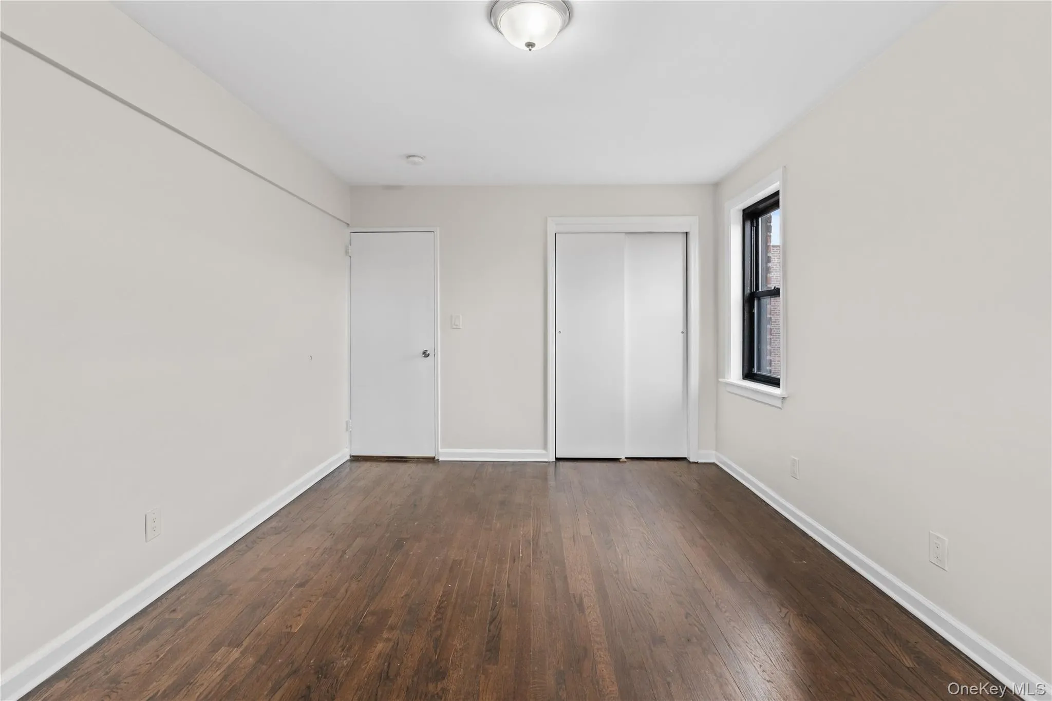 Unfurnished bedroom featuring dark wood-style floors and a closet Unfurnished bedroom featuring dark wood-style floors and a closet