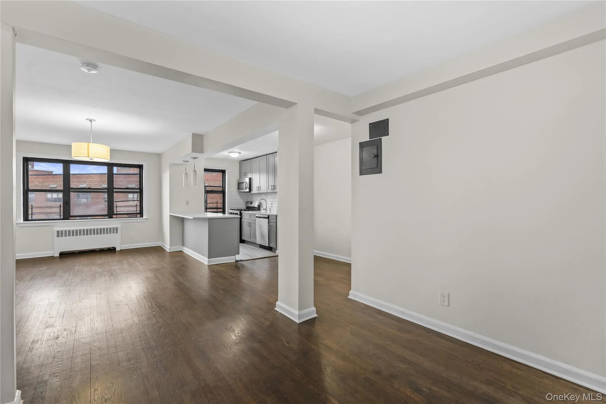 Unfurnished living room featuring radiator heating unit and dark wood finished floors Unfurnished living room featuring radiator heating unit and dark wood finished floors
