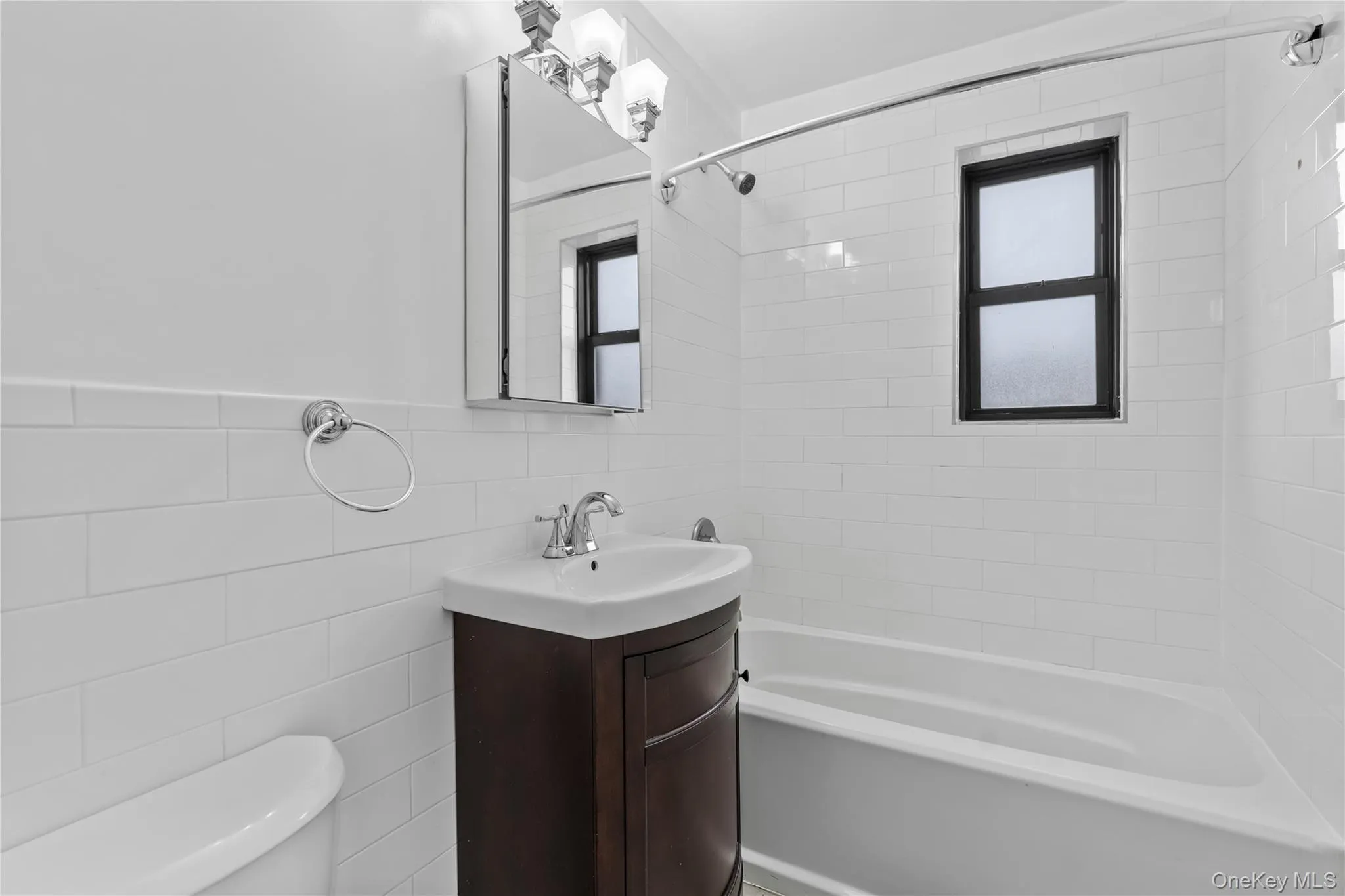 Bathroom with vanity, bathtub / shower combination, healthy amount of natural light, and tile walls Bathroom with vanity, bathtub / shower combination, healthy amount of natural light, and tile walls