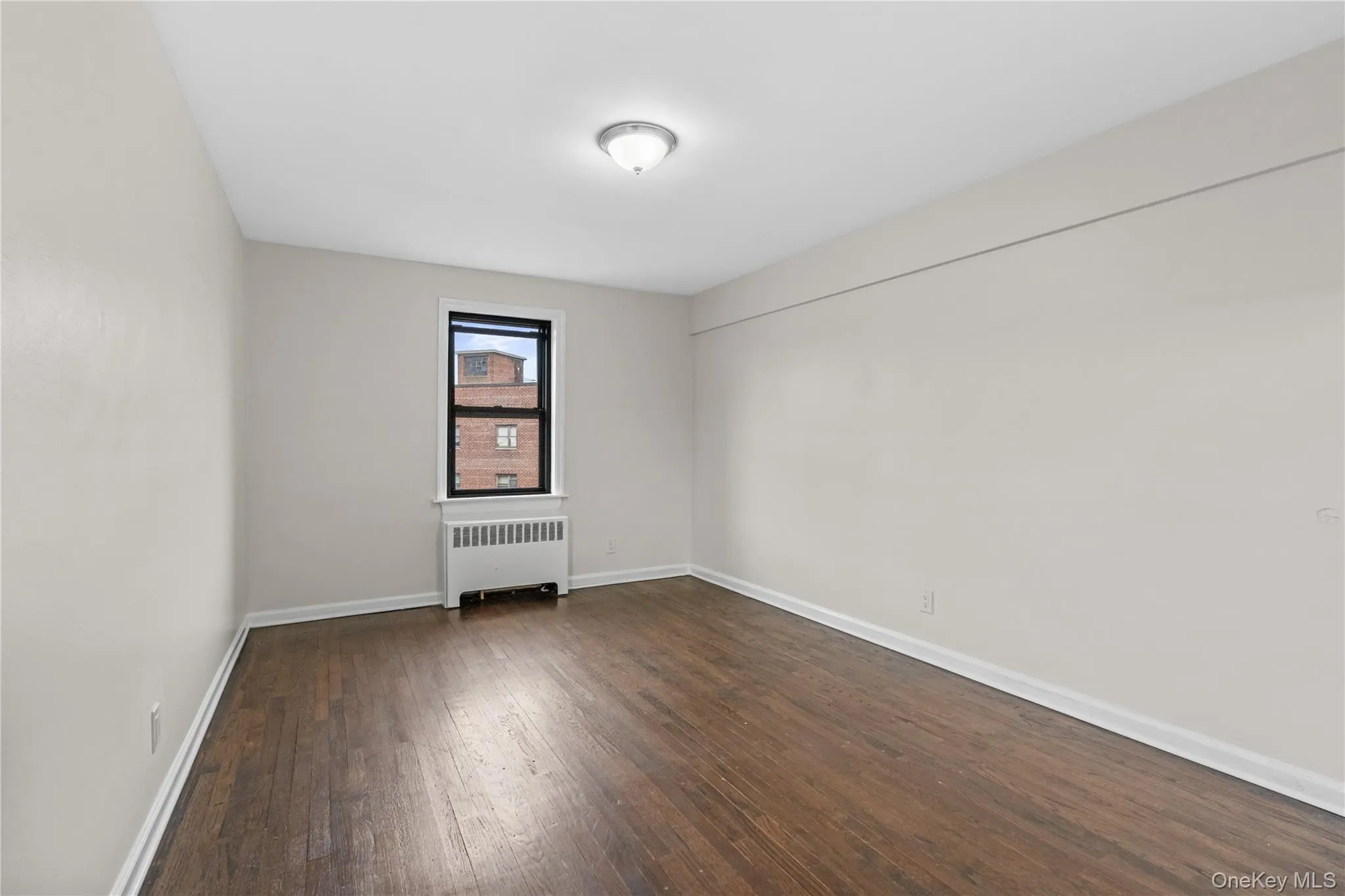 Spare room featuring radiator and dark wood-style floors Spare room featuring radiator and dark wood-style floors