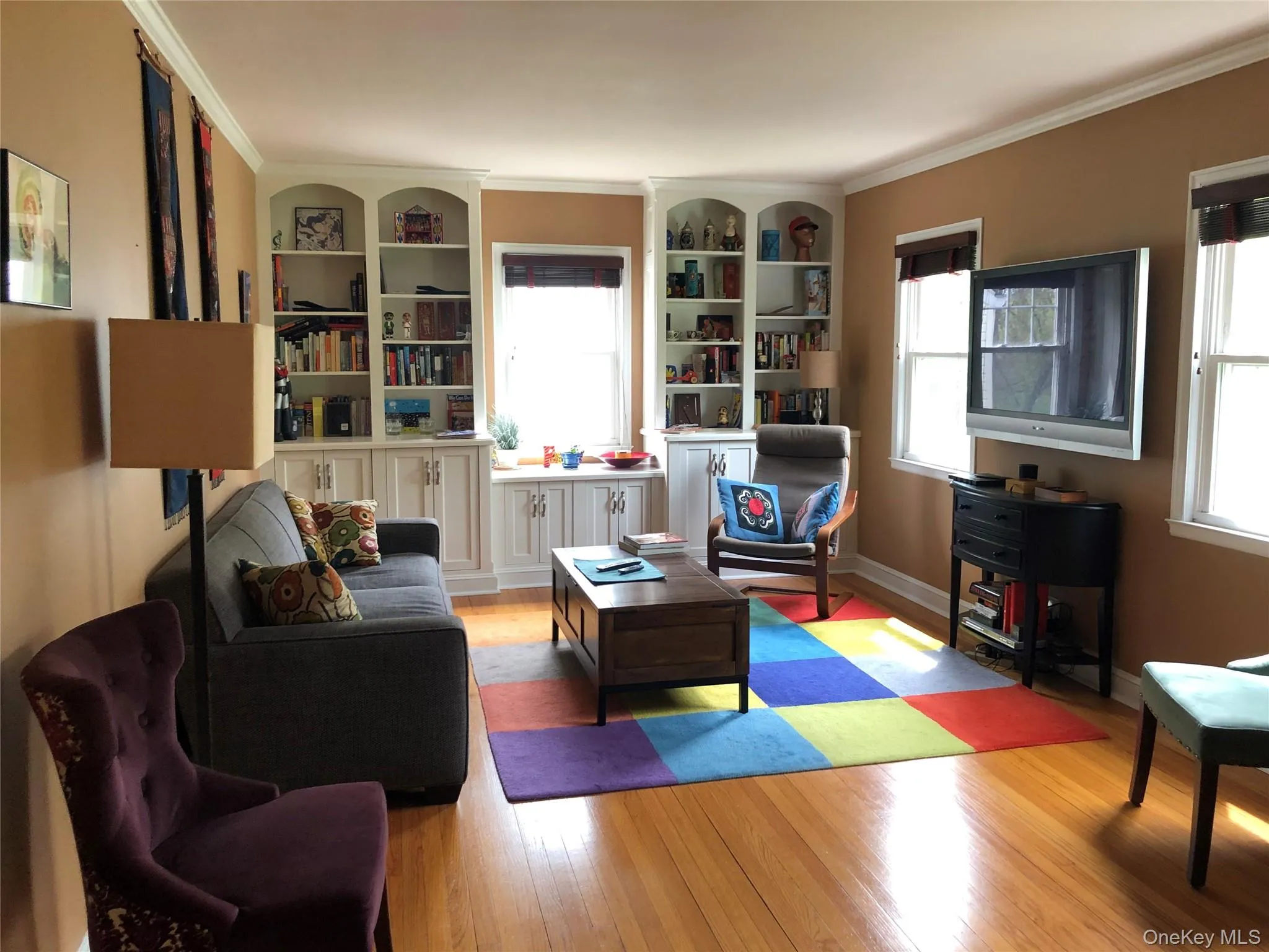 Living area featuring light wood-type flooring, healthy amount of natural light, and ornamental molding Living area featuring light wood-type flooring, healthy amount of natural light, and ornamental molding