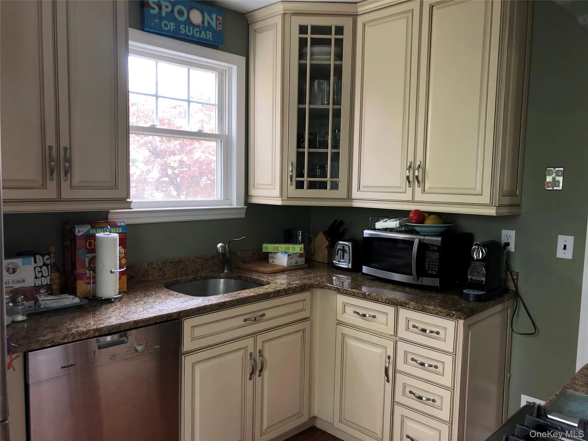 Kitchen with cream cabinets, appliances with stainless steel finishes, glass insert cabinets, and dark stone counters Kitchen with cream cabinets, appliances with stainless steel finishes, glass insert cabinets, and dark stone counters