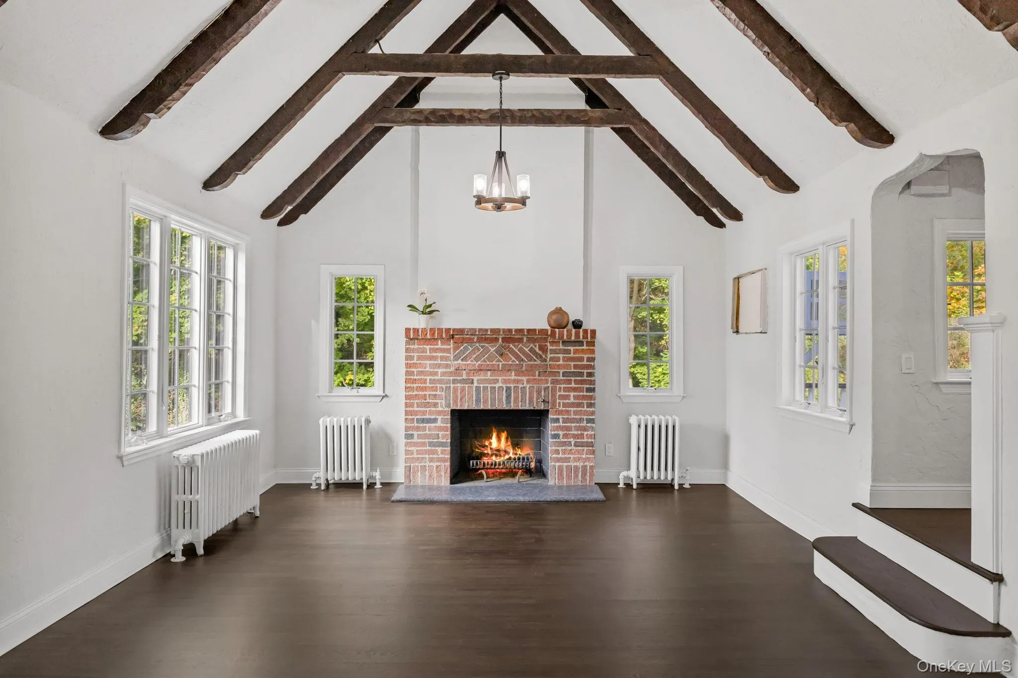 living room with high vaulted ceiling, radiator, dark wood-style flooring, and beam ceiling living room with high vaulted ceiling, radiator, dark wood-style flooring, and beam ceiling