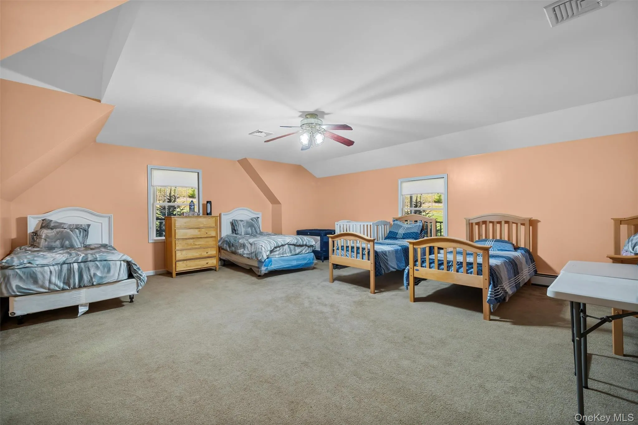 Bedroom featuring lofted ceiling, multiple windows, carpet flooring, and a ceiling fan Bedroom featuring lofted ceiling, multiple windows, carpet flooring, and a ceiling fan