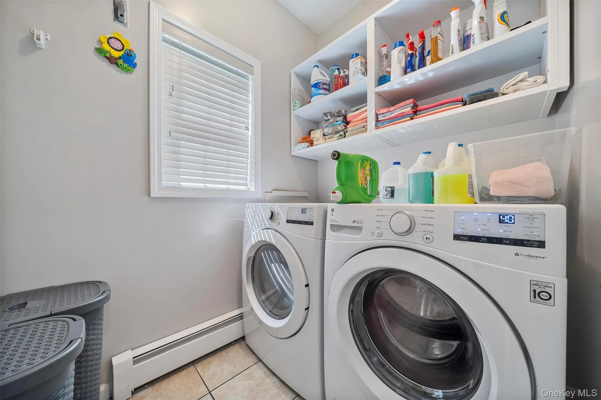 Laundry room featuring baseboard heating, light tile patterned flooring, and washing machine and clothes dryer Laundry room featuring baseboard heating, light tile patterned flooring, and washing machine and clothes dryer