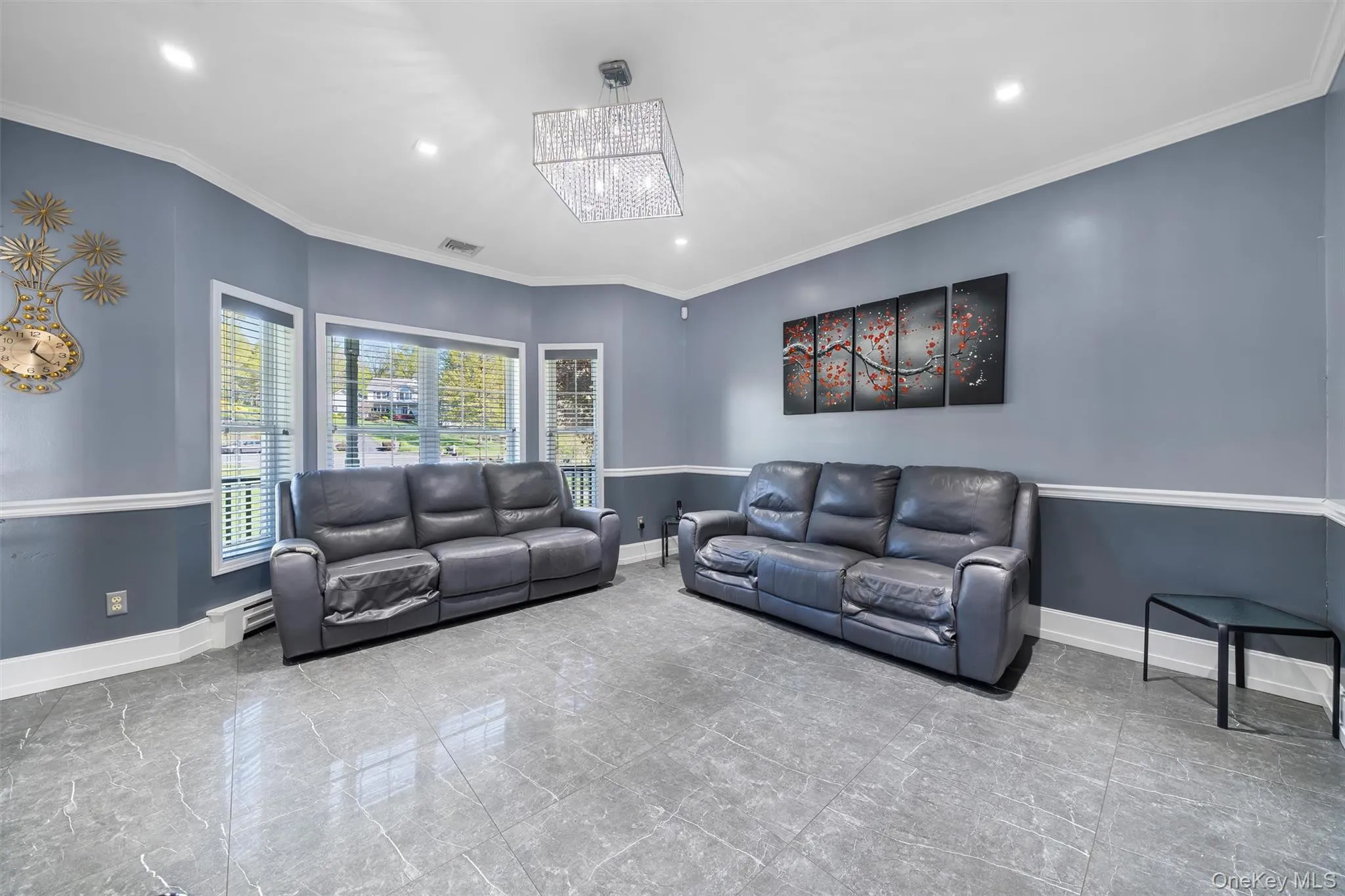 Living room featuring ornamental molding, recessed lighting, a baseboard radiator, a chandelier, and marble finish flooring Living room featuring ornamental molding, recessed lighting, a baseboard radiator, a chandelier, and marble finish flooring