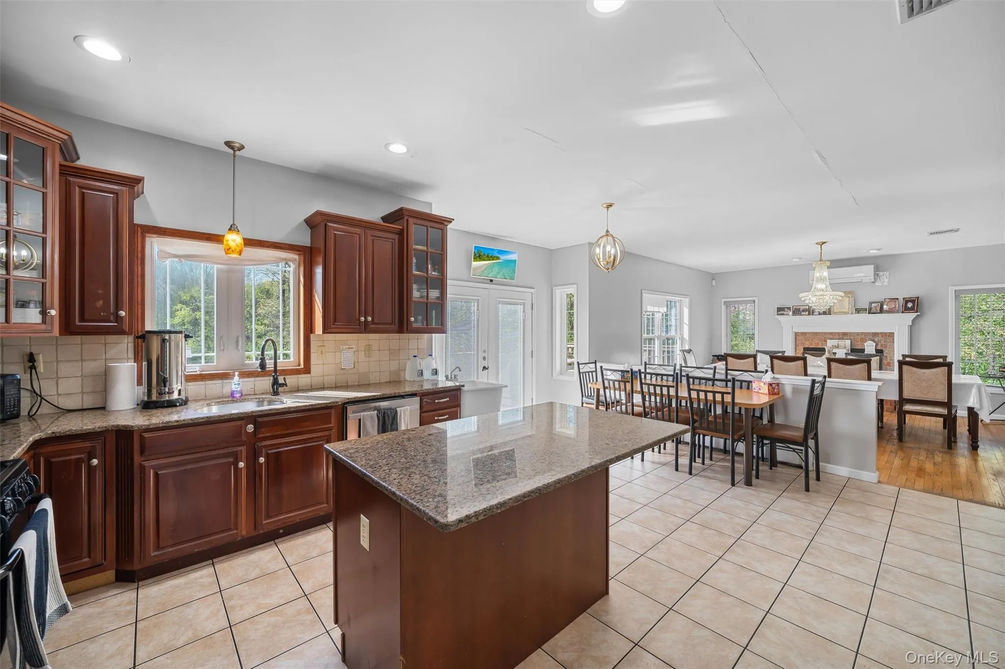 Kitchen featuring decorative light fixtures, glass insert cabinets, light tile patterned flooring, dark stone counters, and healthy amount of natural light Kitchen featuring decorative light fixtures, glass insert cabinets, light tile patterned flooring, dark stone counters, and healthy amount of natural light