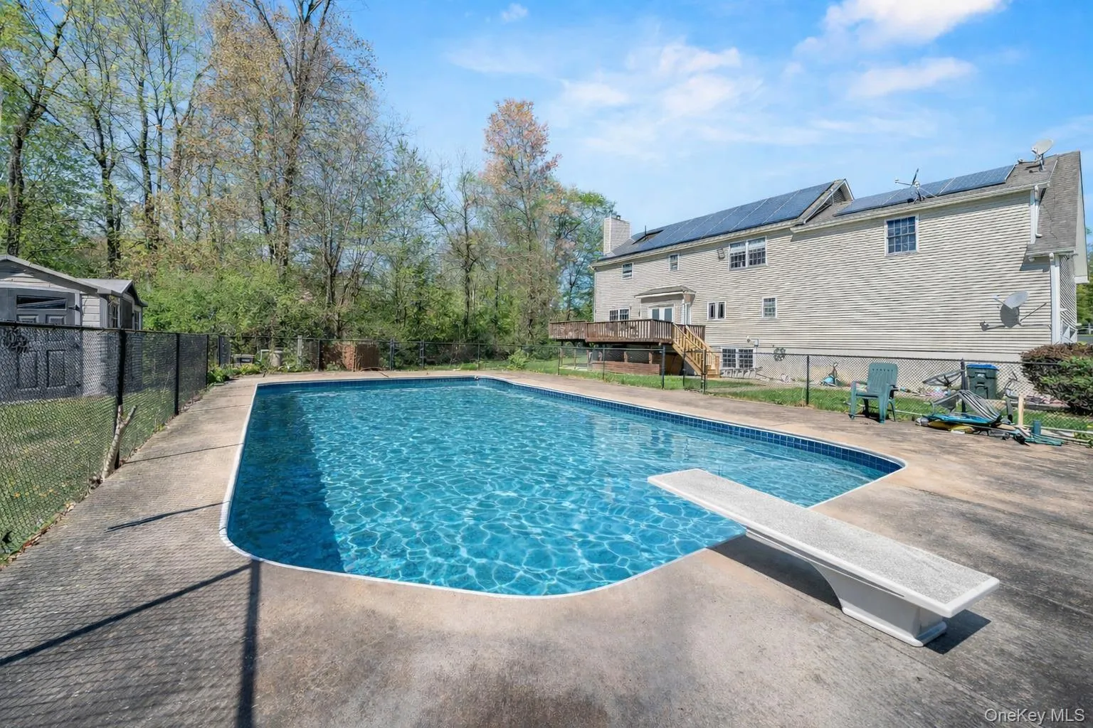 View of pool with a deck, a fenced backyard, a diving board, a patio, and stairway View of pool with a deck, a fenced backyard, a diving board, a patio, and stairway