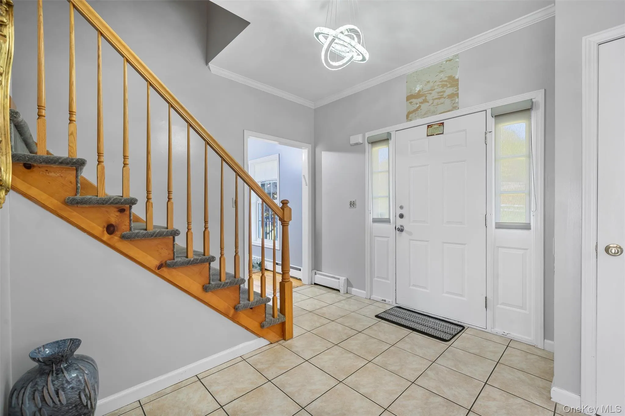 Foyer entrance featuring crown molding, stairs, light tile patterned flooring, and a chandelier Foyer entrance featuring crown molding, stairs, light tile patterned flooring, and a chandelier