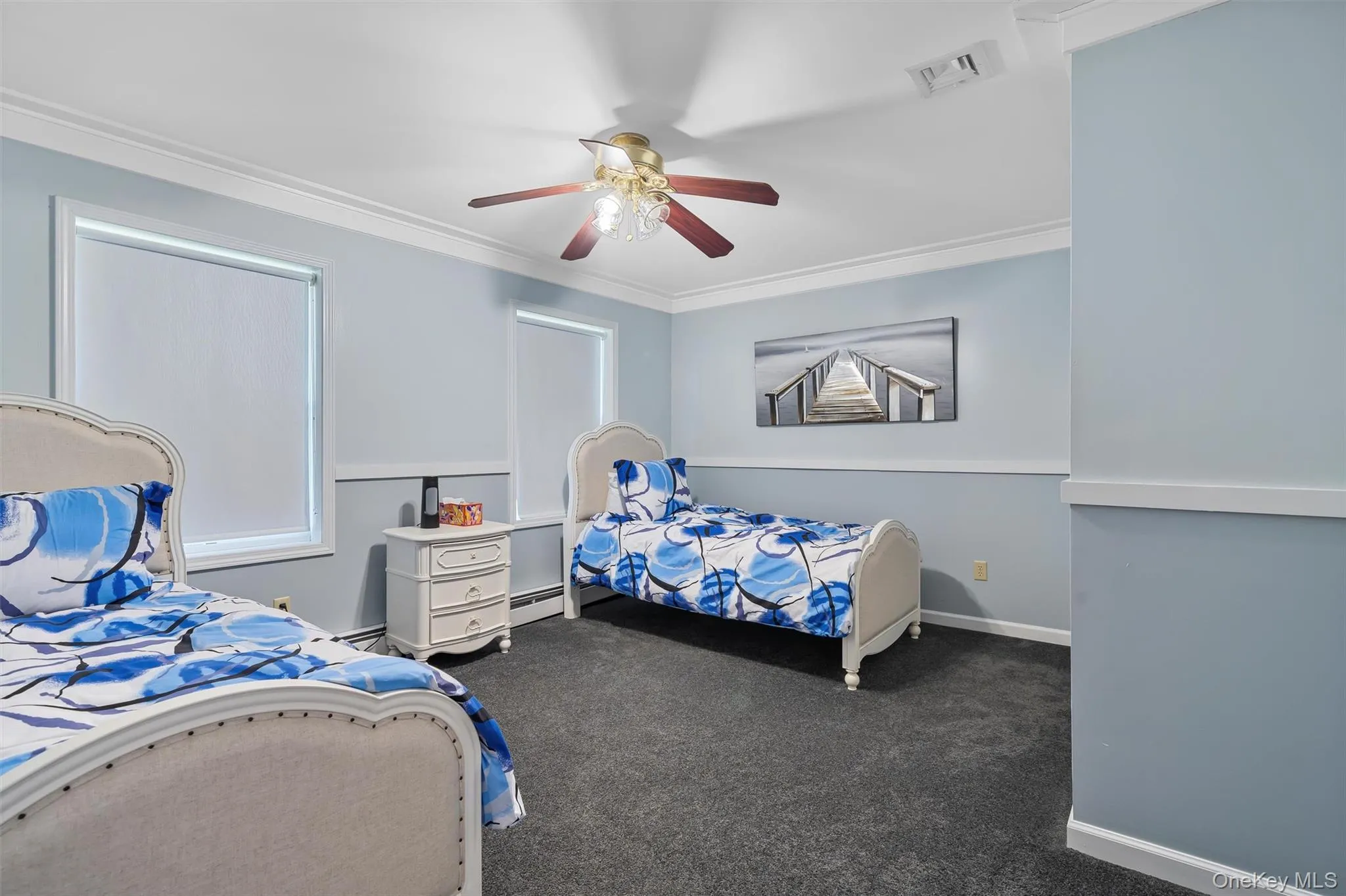 Bedroom featuring a ceiling fan, ornamental molding, dark carpet, and a baseboard heating unit Bedroom featuring a ceiling fan, ornamental molding, dark carpet, and a baseboard heating unit