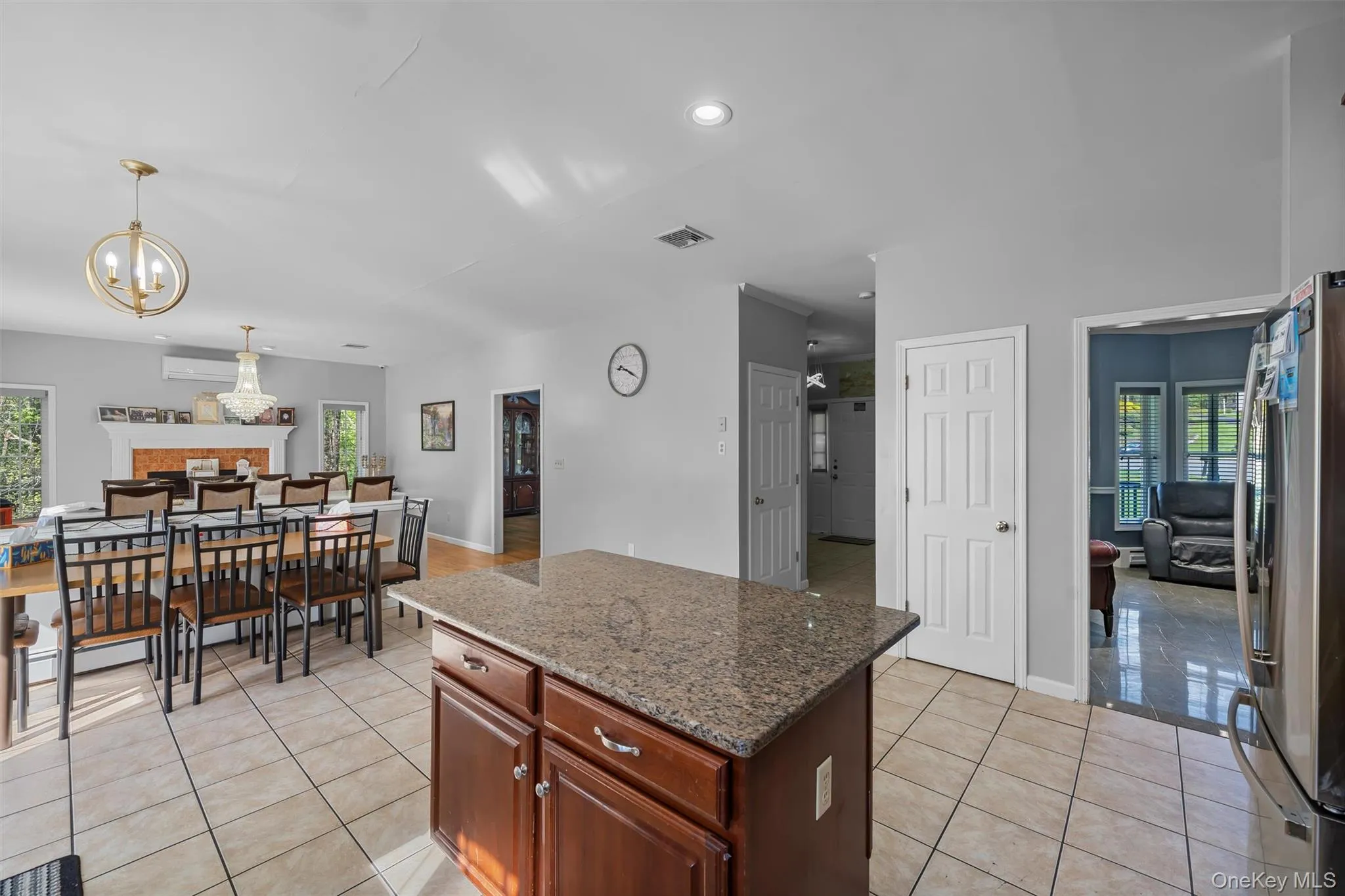 Kitchen with dark stone countertops, freestanding refrigerator, a kitchen island, light tile patterned floors, and recessed lighting Kitchen with dark stone countertops, freestanding refrigerator, a kitchen island, light tile patterned floors, and recessed lighting