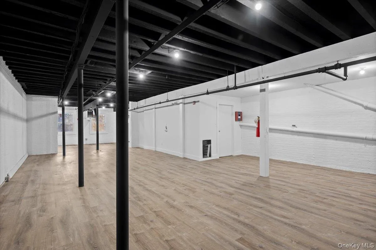 Finished below grade area with light wood-style flooring and brick wall Finished below grade area with light wood-style flooring and brick wall