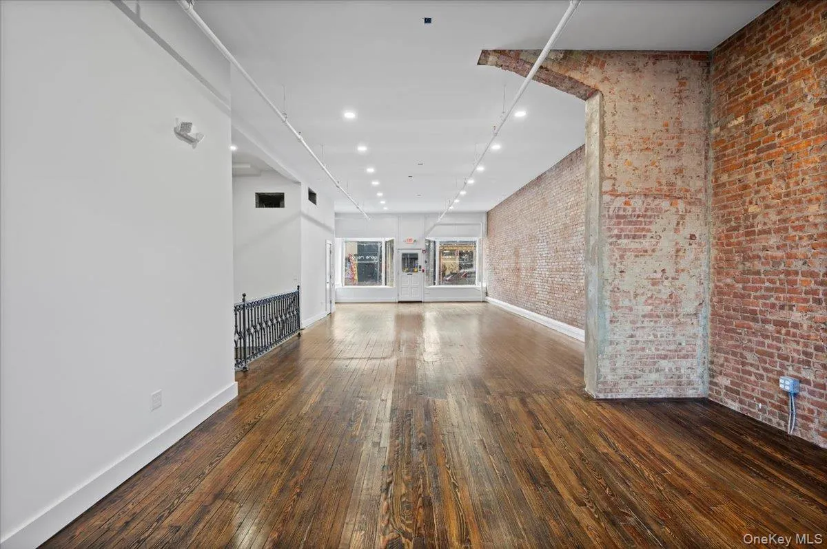 Unfurnished living room featuring recessed lighting, brick wall, and dark wood finished floors Unfurnished living room featuring recessed lighting, brick wall, and dark wood finished floors