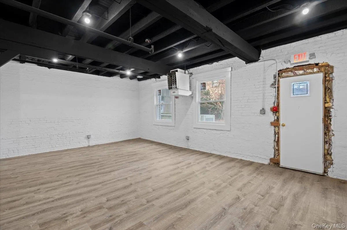 Basement with brick wall, wood finished floors, and a heating unit Basement with brick wall, wood finished floors, and a heating unit