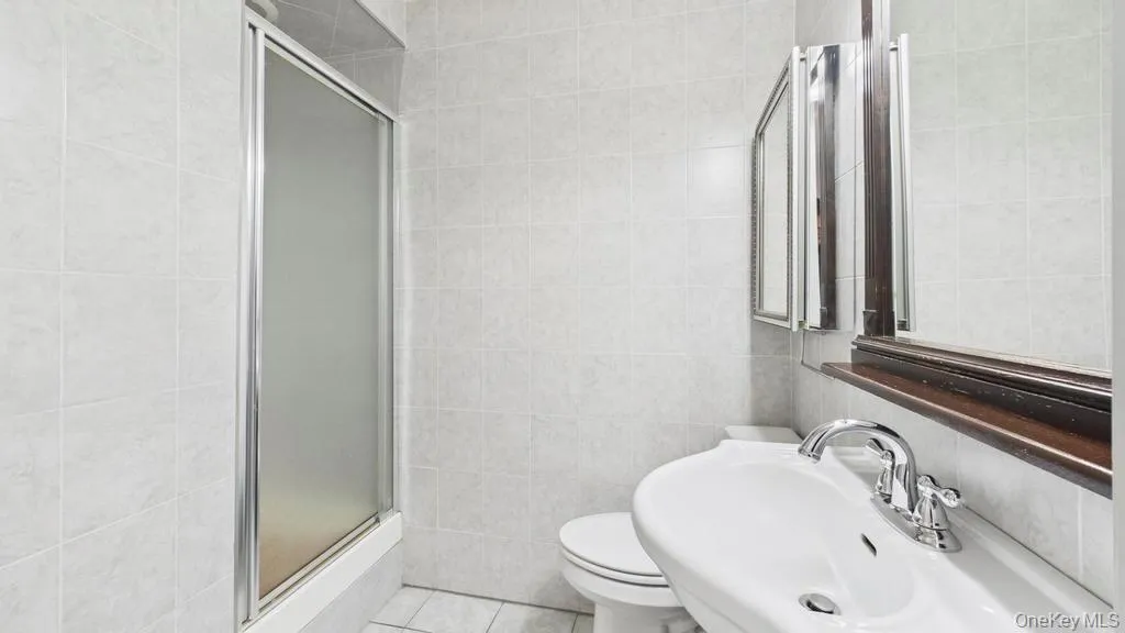 Full bathroom featuring a shower stall, tile walls, and tile patterned floors Full bathroom featuring a shower stall, tile walls, and tile patterned floors