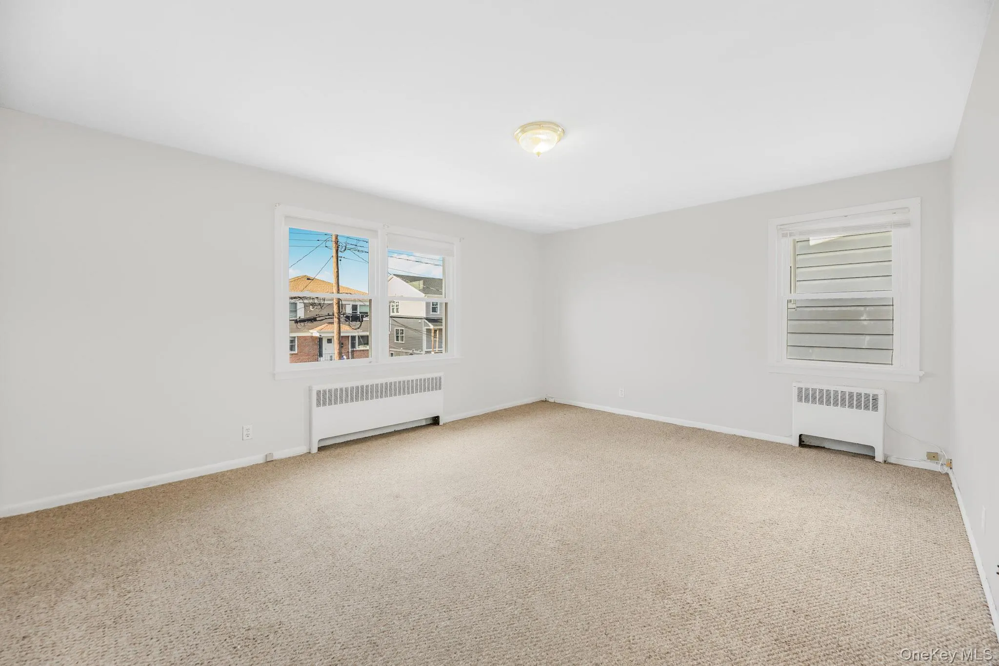Spare room featuring radiator heating unit and light colored carpet Spare room featuring radiator heating unit and light colored carpet