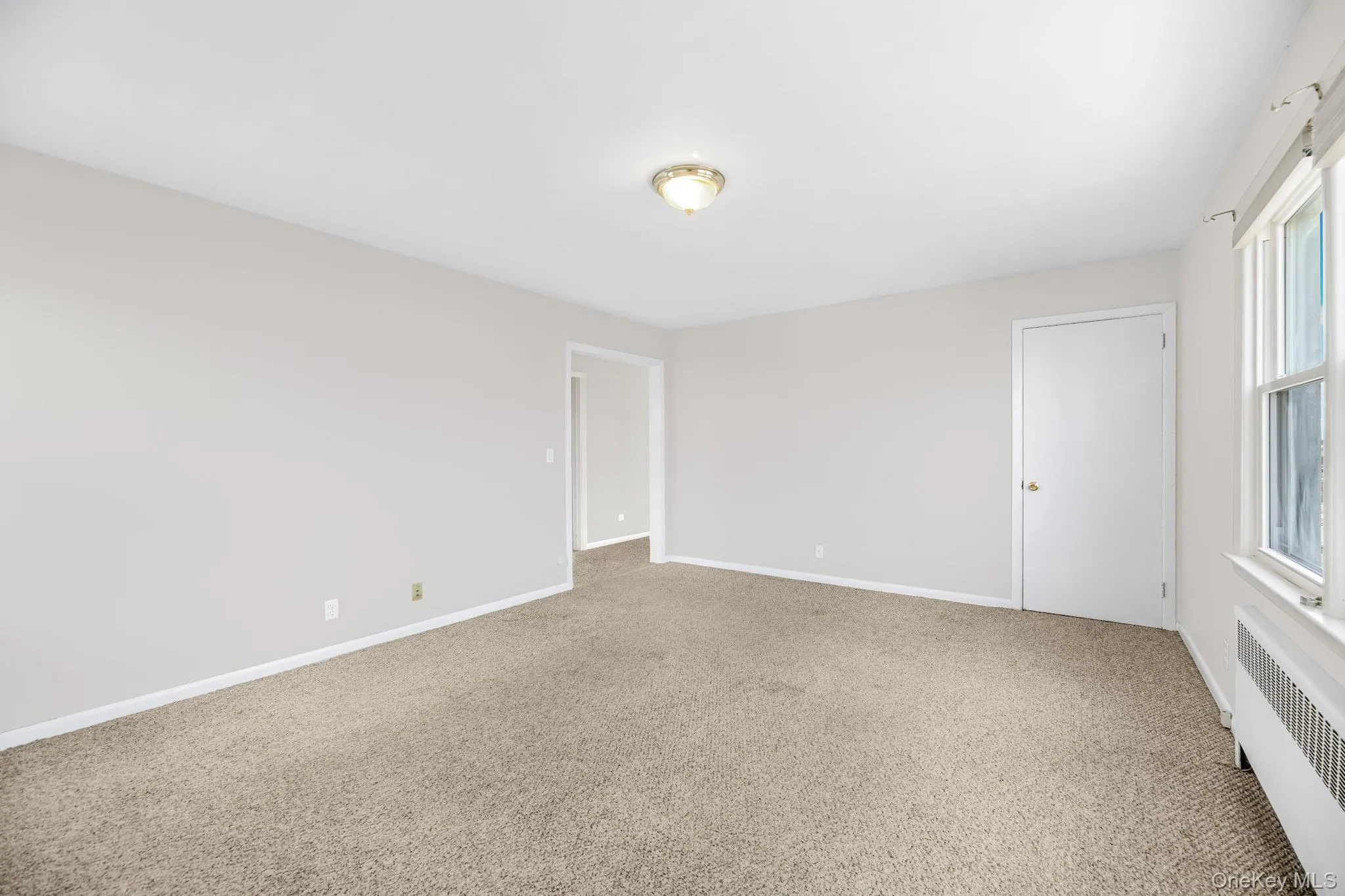 Empty room featuring radiator and carpet Empty room featuring radiator and carpet