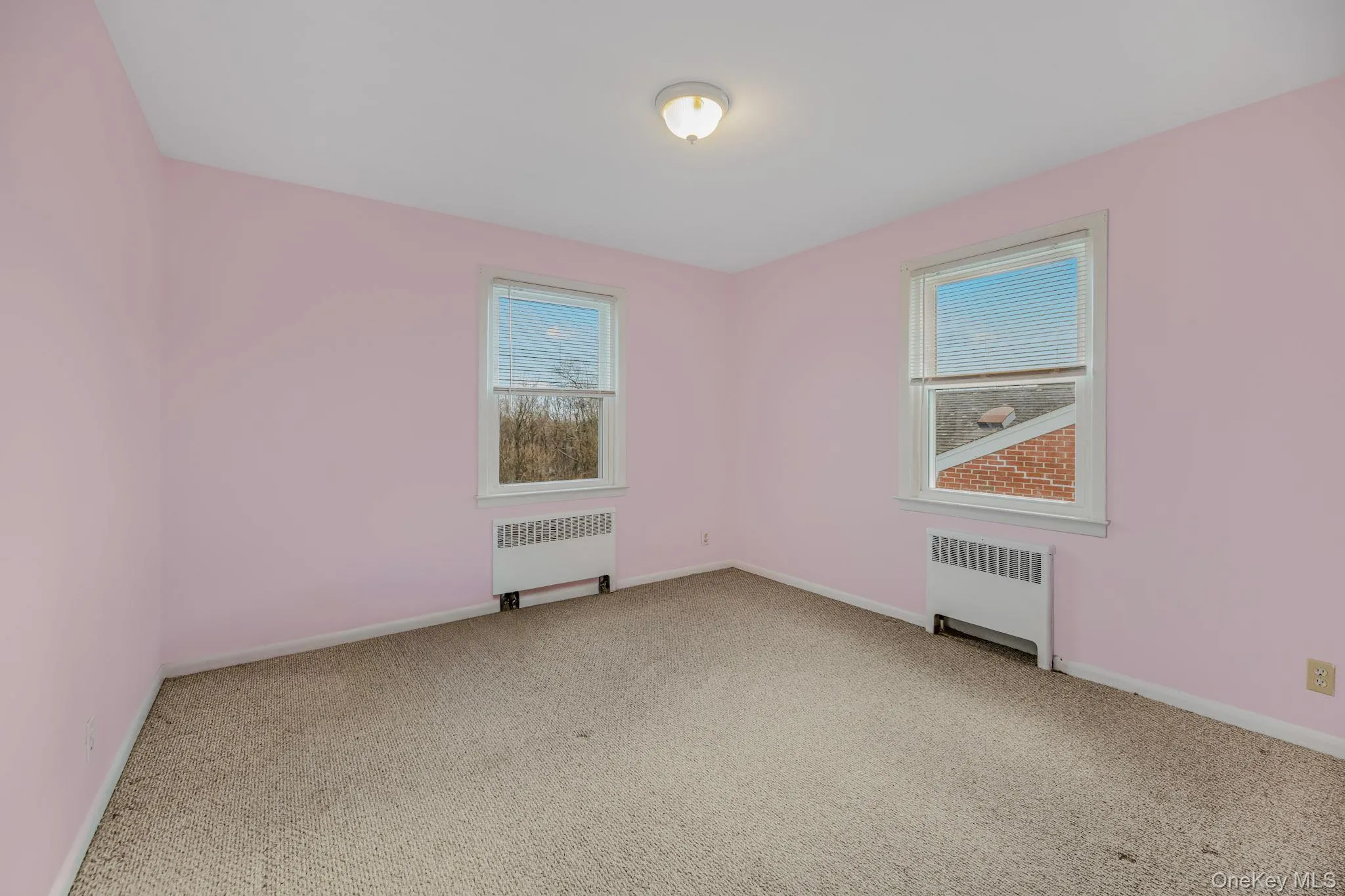 Unfurnished room featuring radiator heating unit and light colored carpet Unfurnished room featuring radiator heating unit and light colored carpet