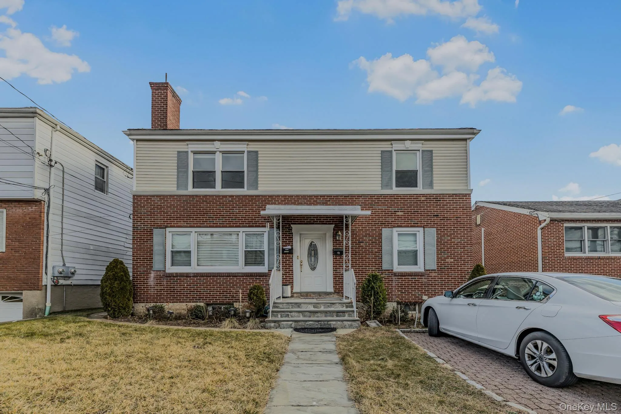 Traditional-style house featuring a chimney, brick siding, and a front lawn Traditional-style house featuring a chimney, brick siding, and a front lawn
