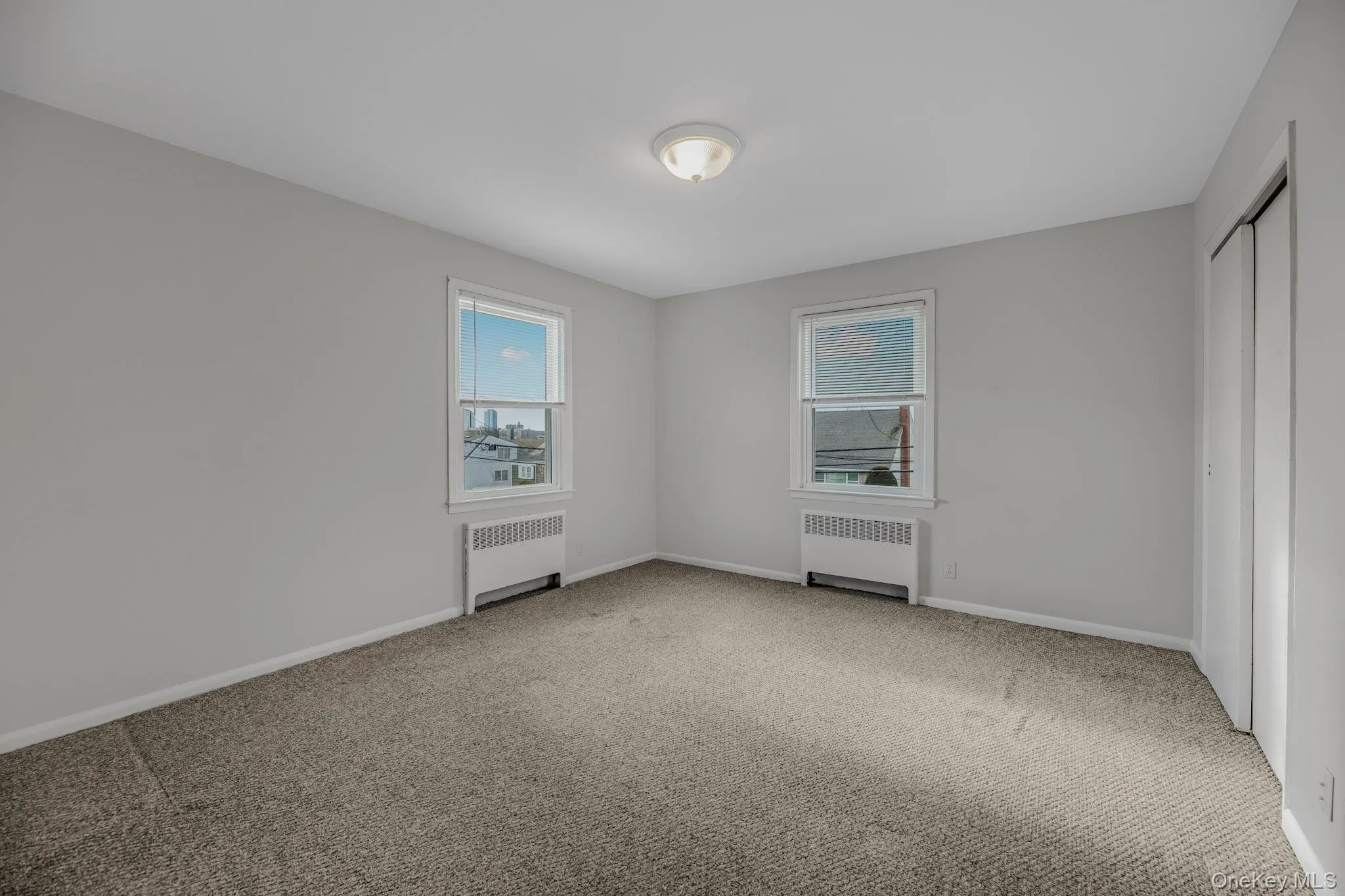 Unfurnished bedroom with radiator heating unit, carpet, and a closet Unfurnished bedroom with radiator heating unit, carpet, and a closet