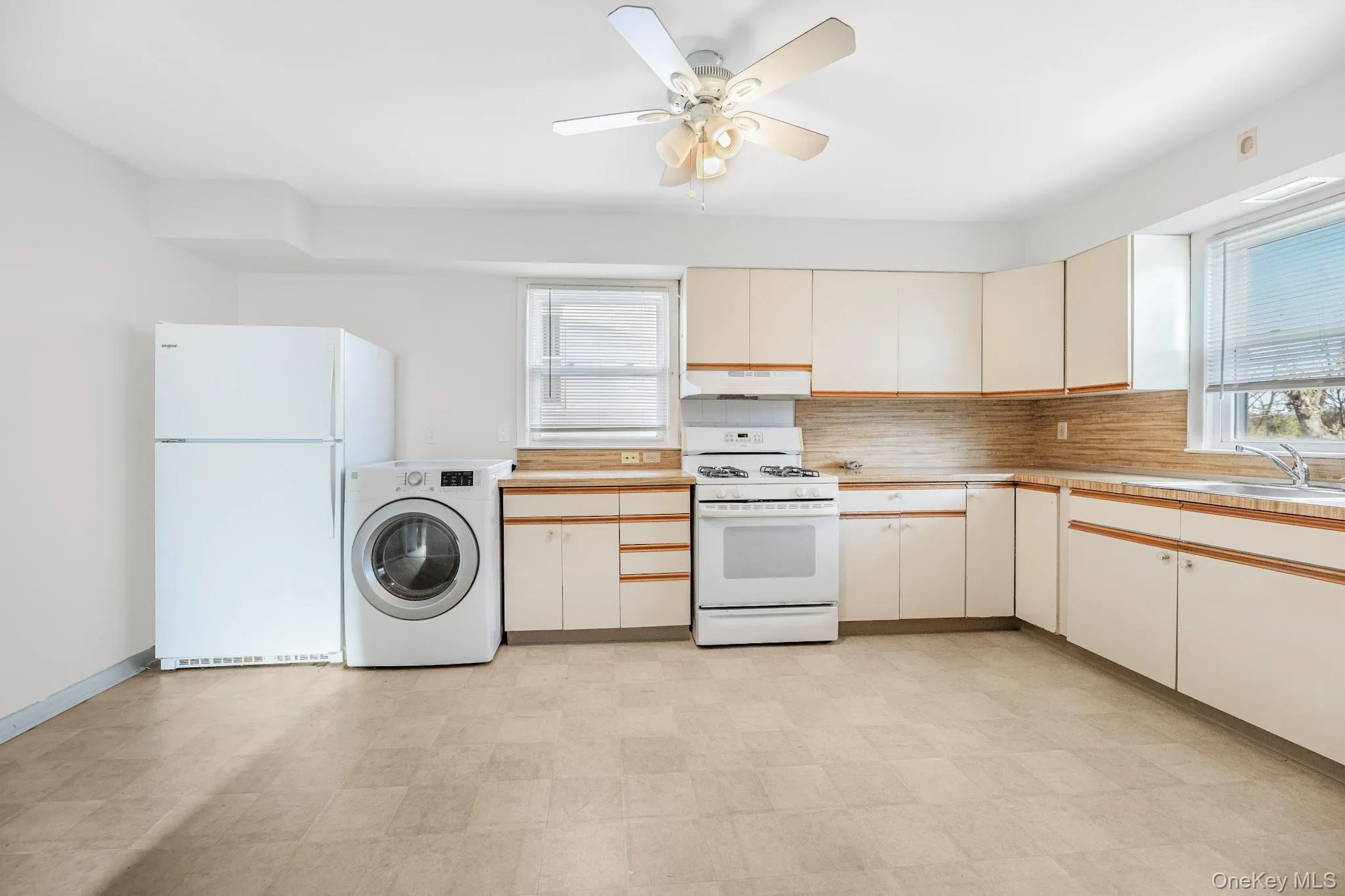 Kitchen with white appliances, washer / dryer, light countertops, and light flooring Kitchen with white appliances, washer / dryer, light countertops, and light flooring