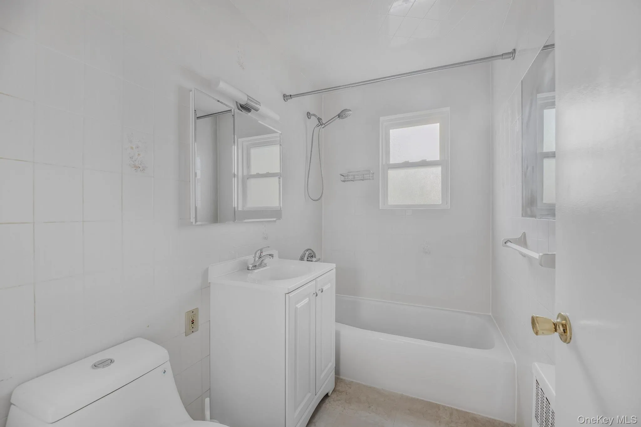 Full bath featuring tile walls, vanity, and tub / shower combination Full bath featuring tile walls, vanity, and tub / shower combination